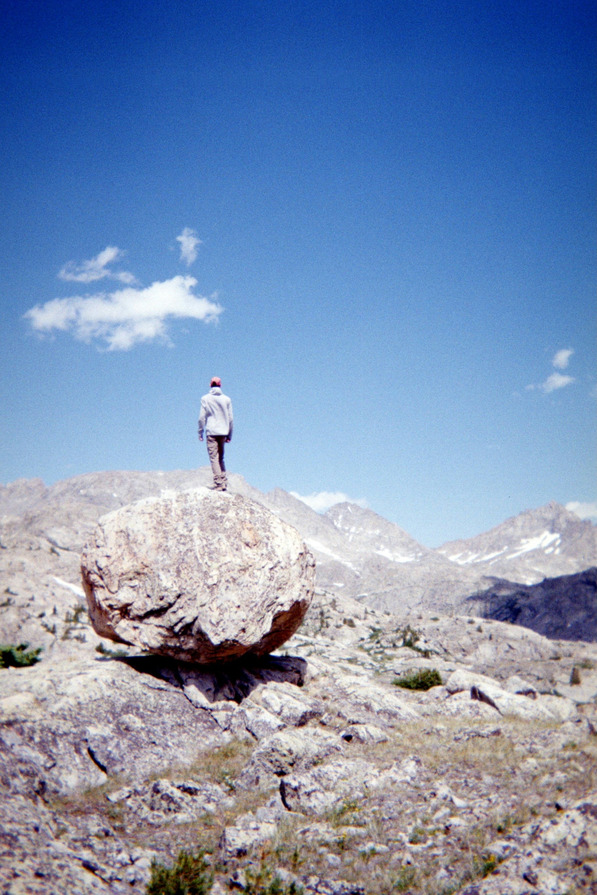 Person standing on large boulder in mountainous landscape