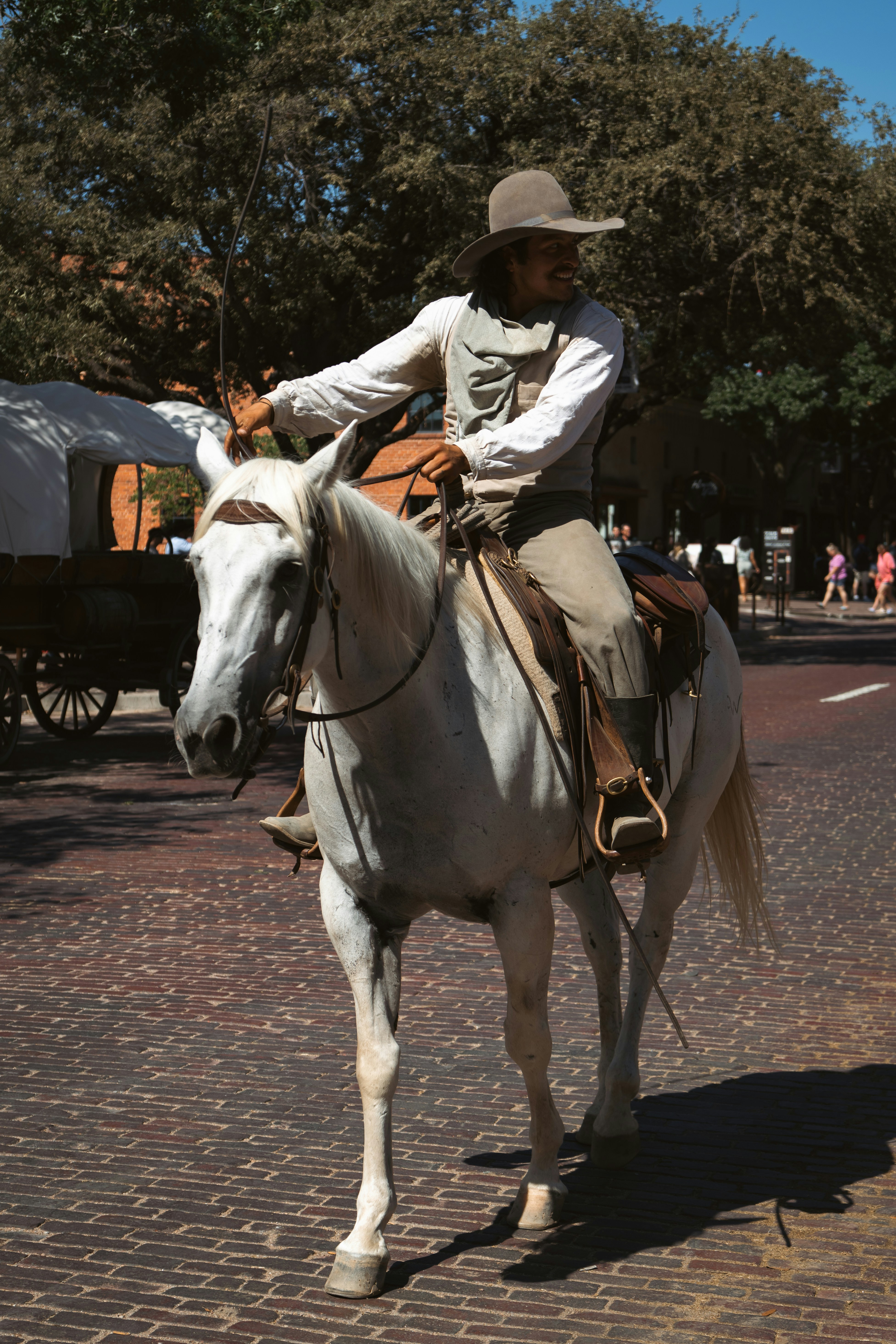 Man in cowboy attire riding a white horse