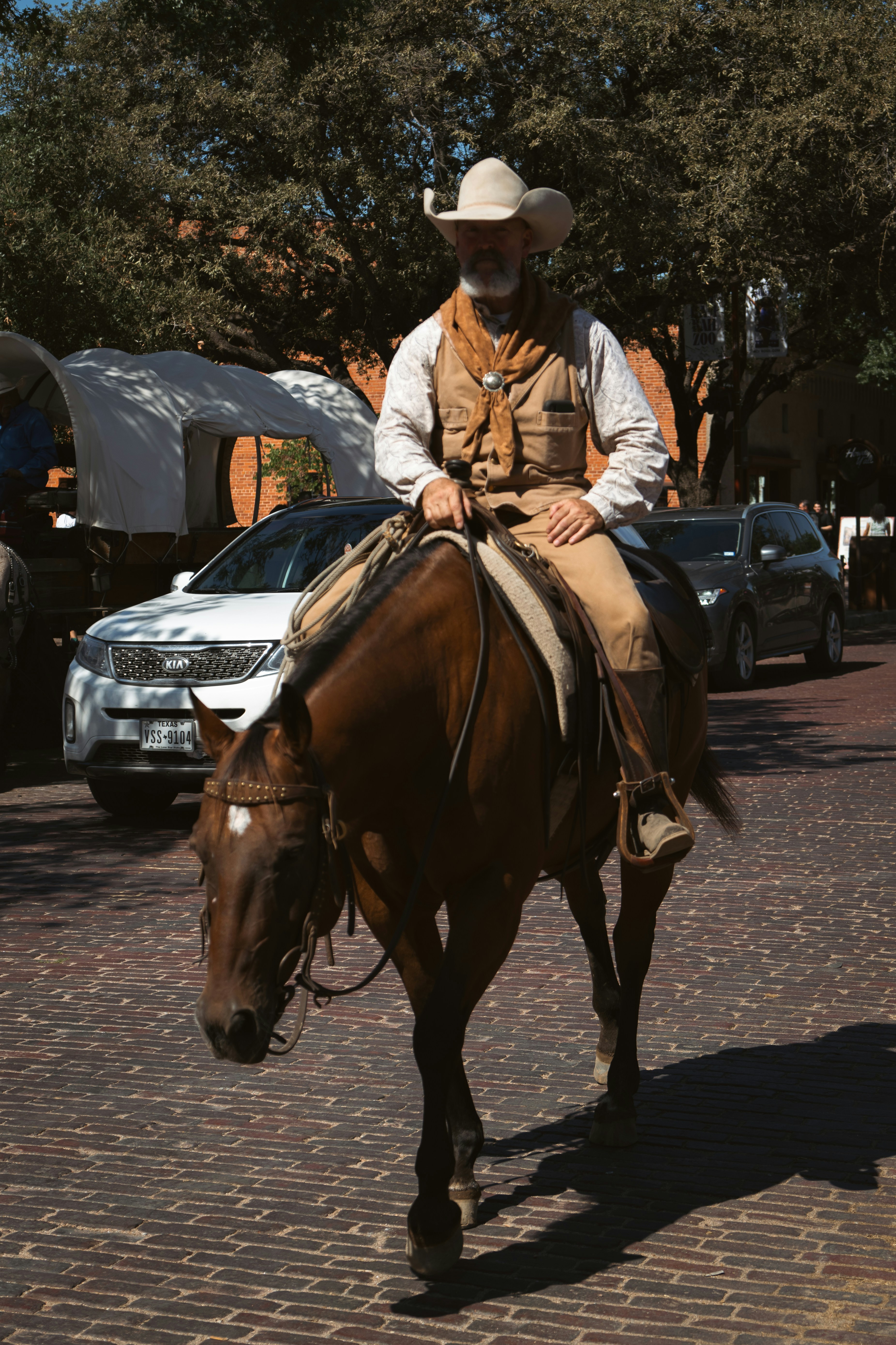 Cowboy riding a horse down a brick street.
