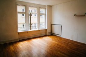 Empty room with wooden floor and large window.