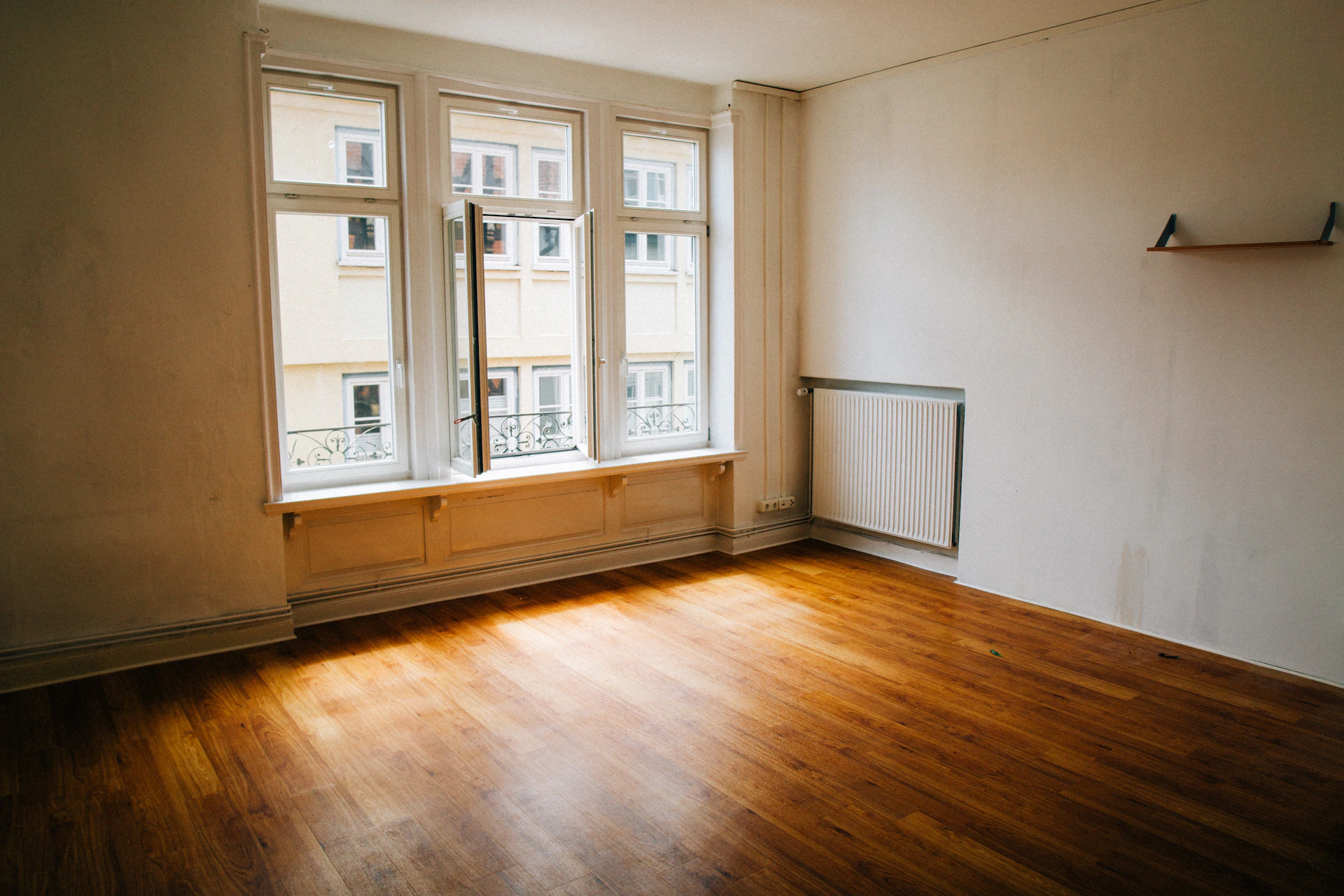Empty room with wooden floor and large window.