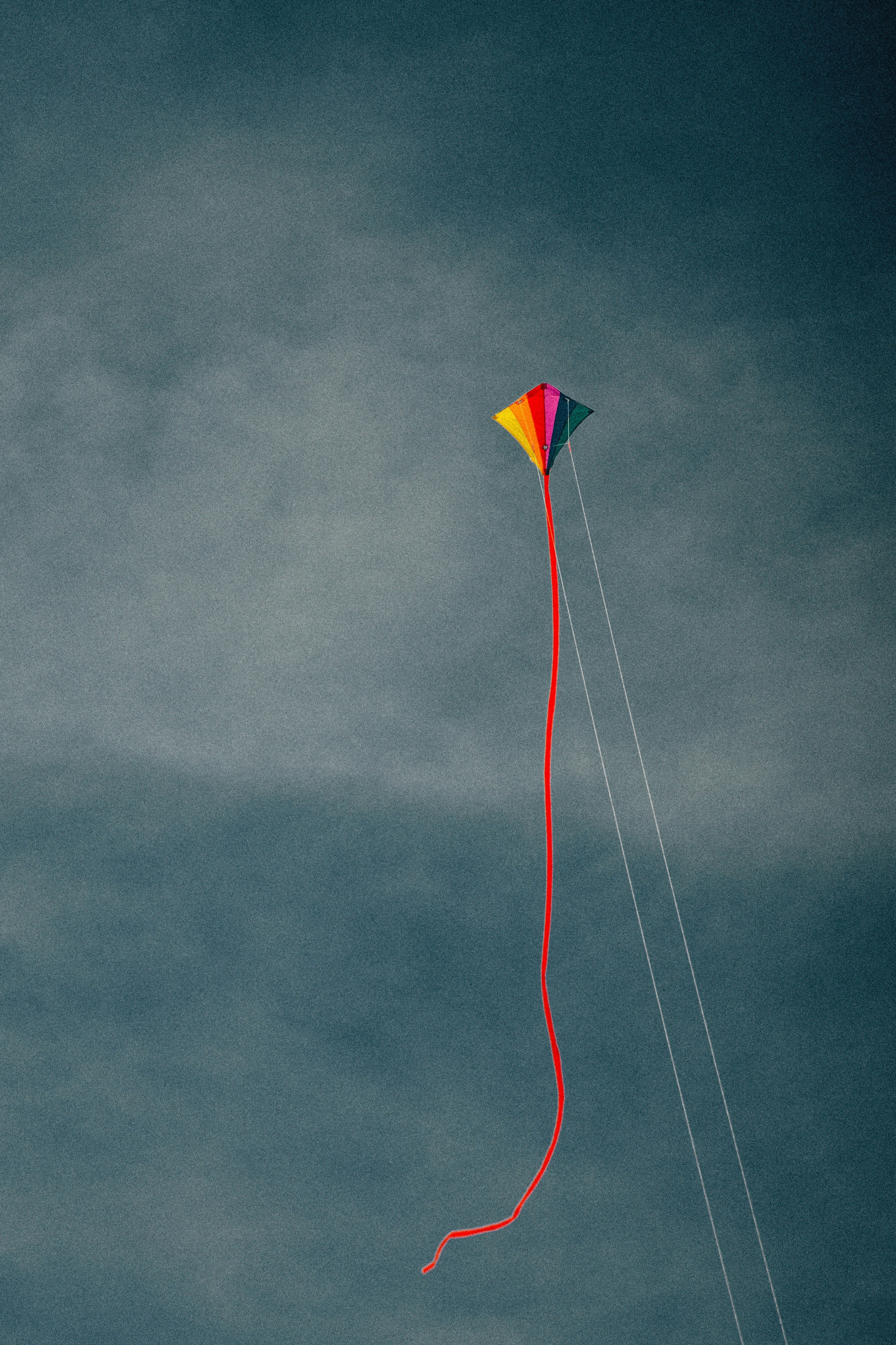 A colorful kite flying against a cloudy sky.