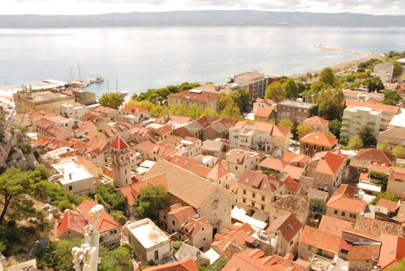 Rooftops of a coastal town with the sea beyond.