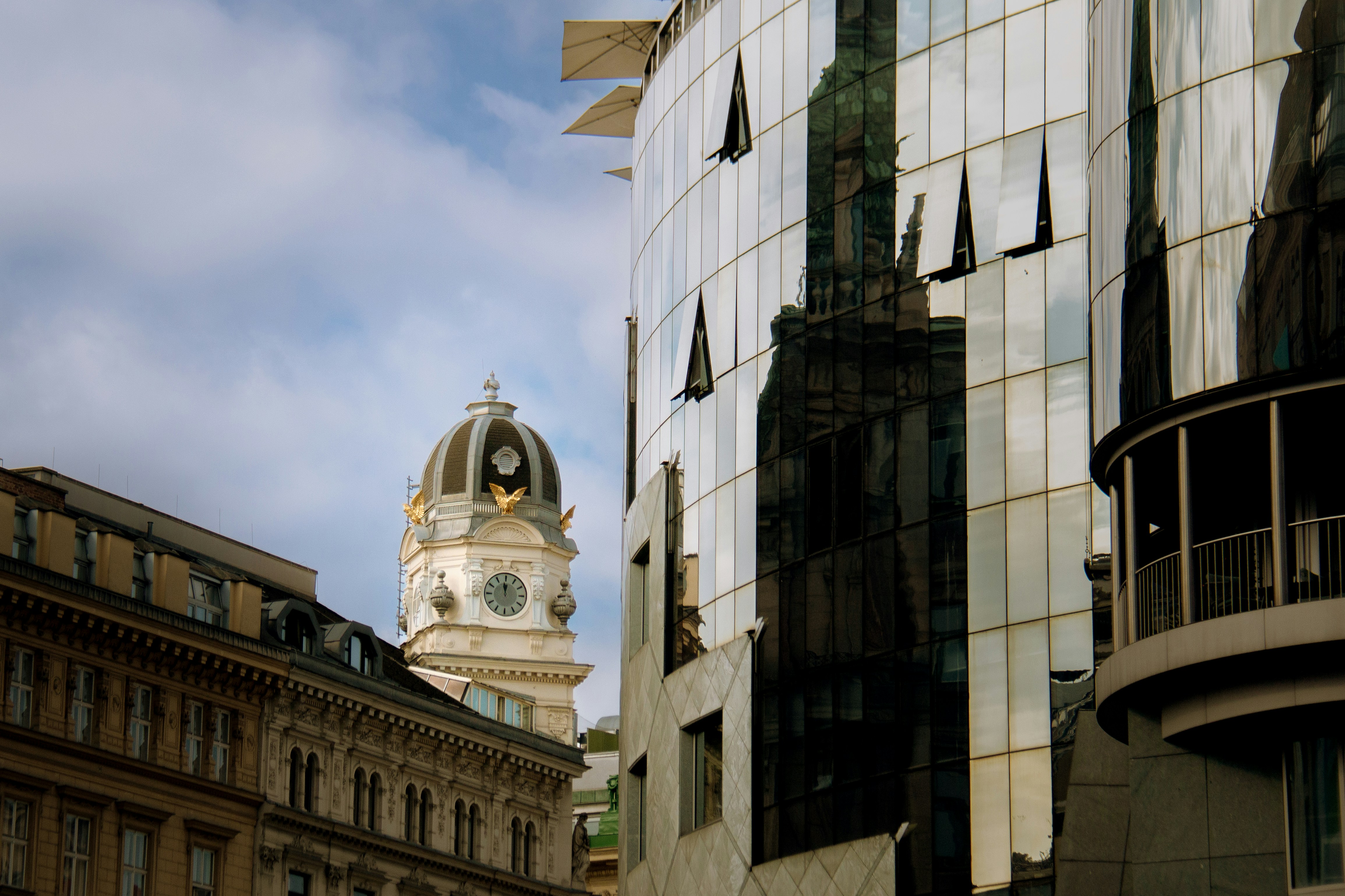 Modern glass building reflects old clock tower
