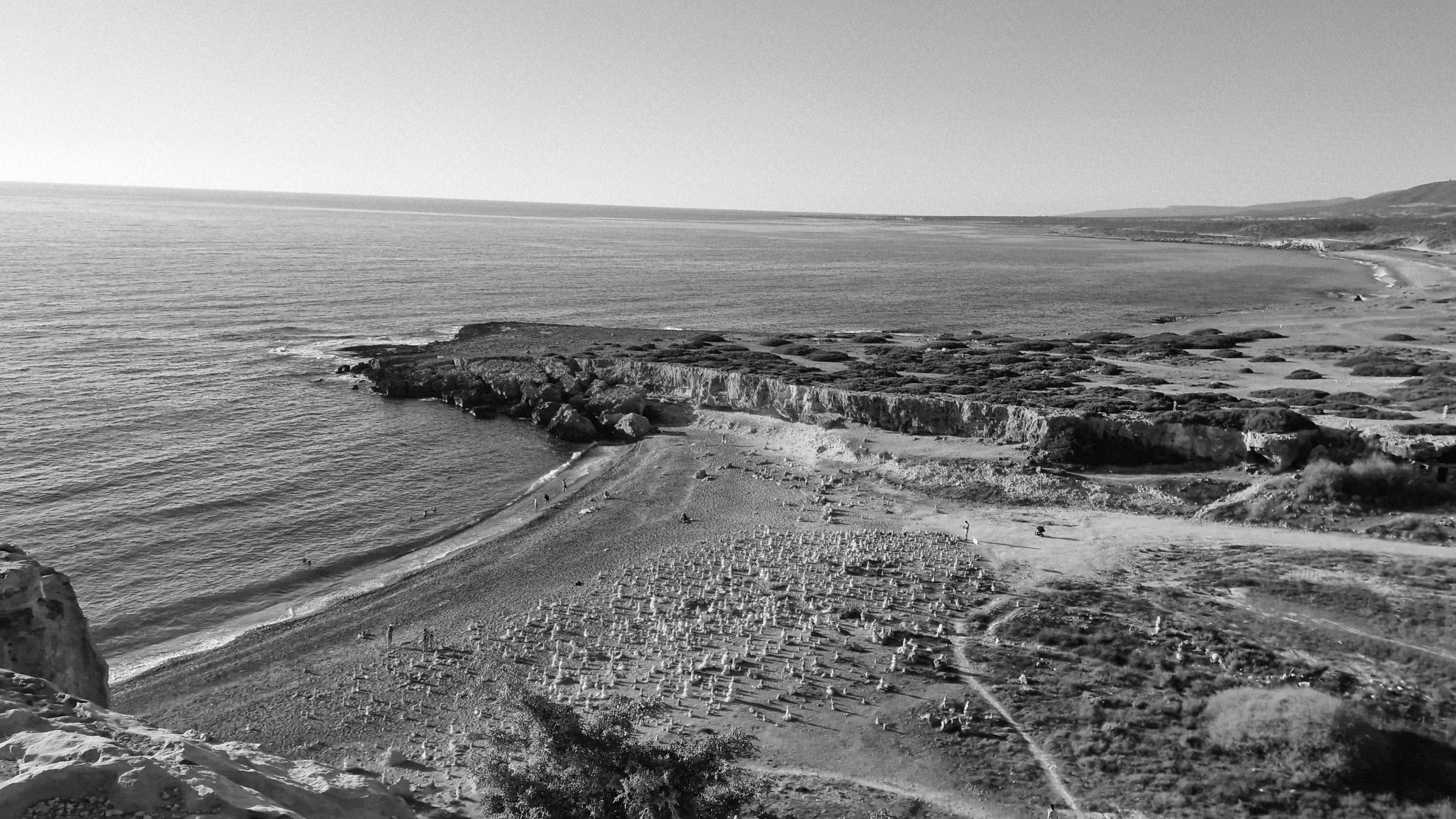 Rocky coastline meeting the calm ocean under a bright sky