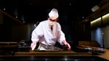 Chef preparing sushi at a counter.