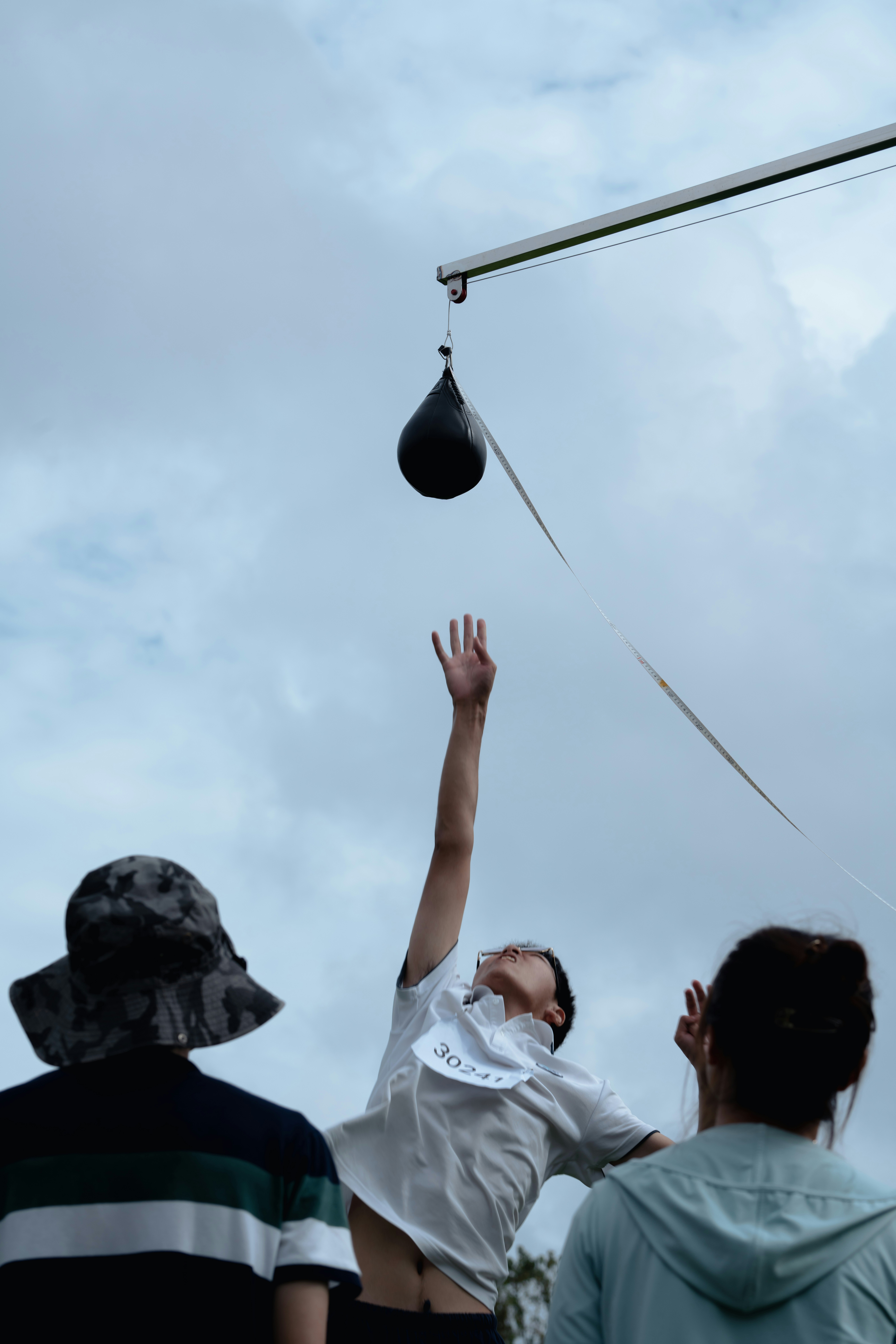 L’homme tend la main vers un sac de frappe contre le ciel nuageux.