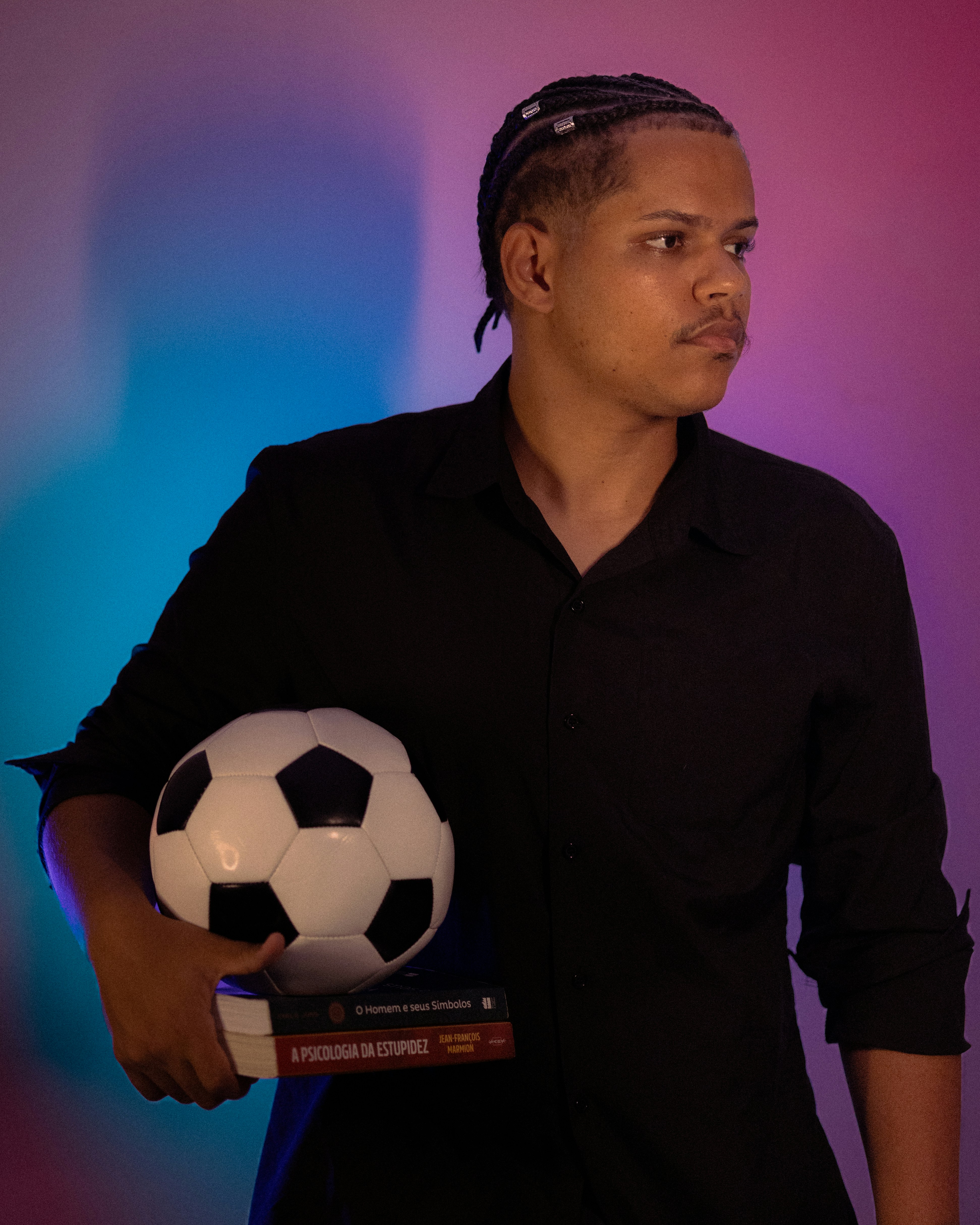 Man holding soccer ball and books with colorful background