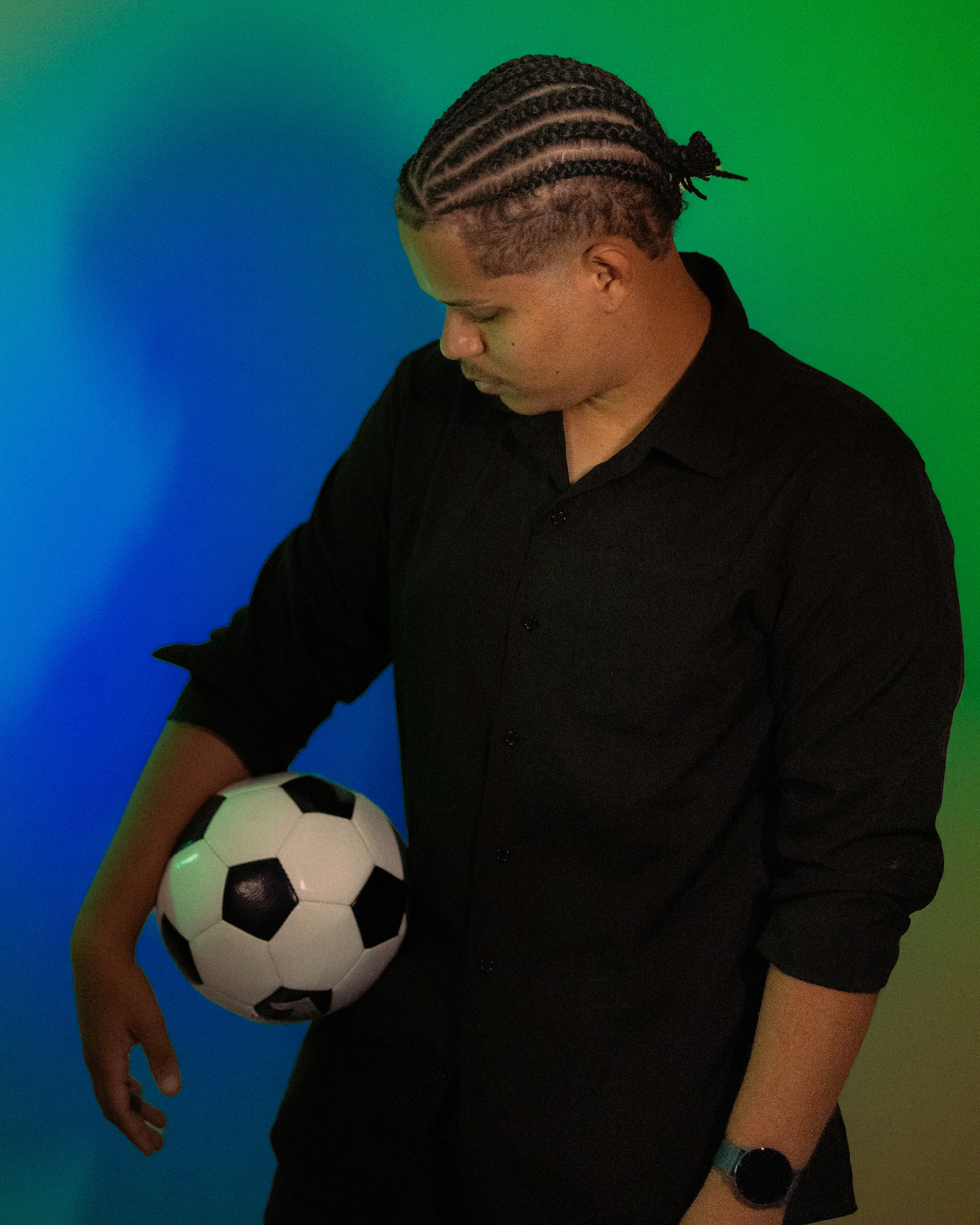Man with braided hair holding a soccer ball.