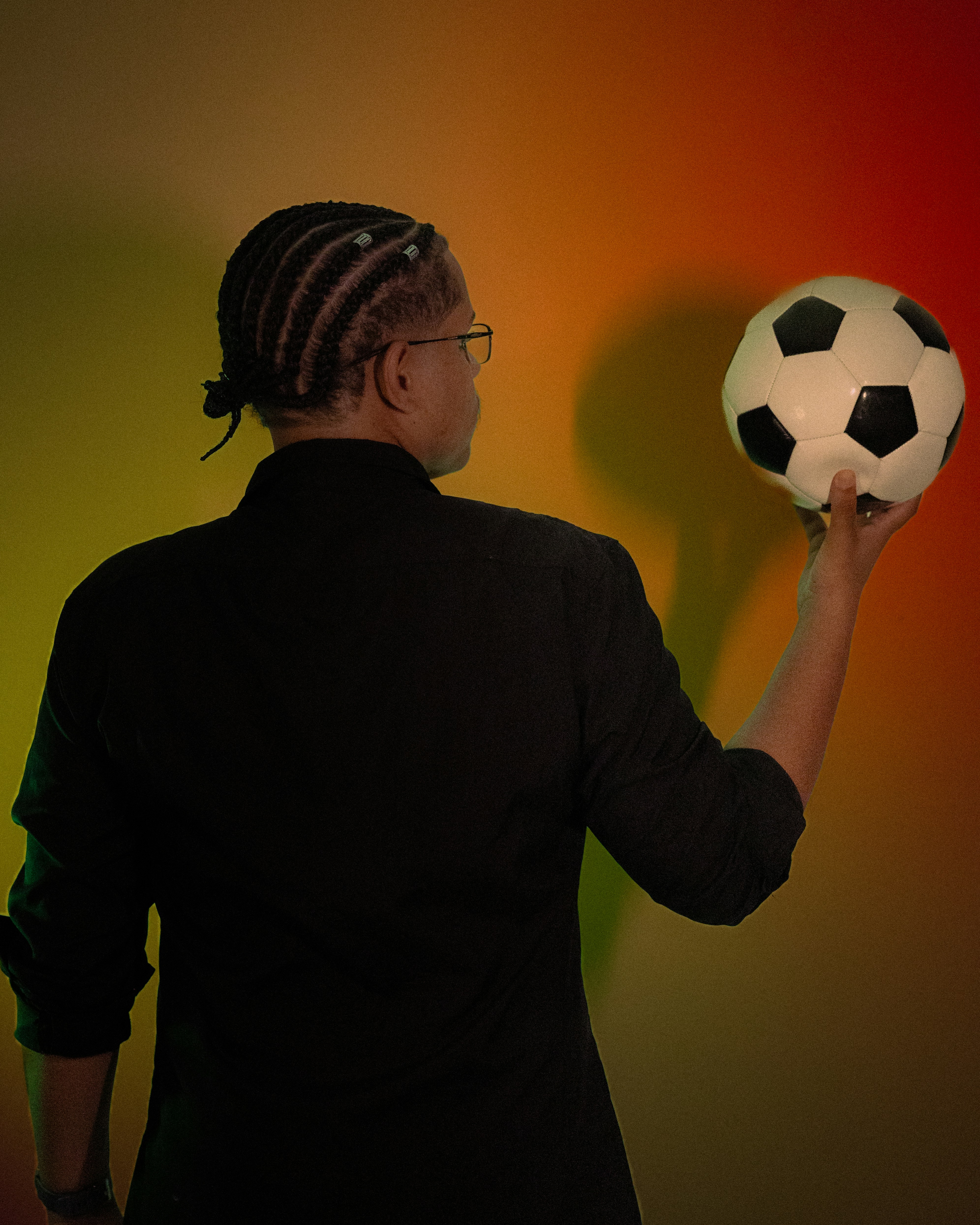 person with braided hair holding a soccer ball