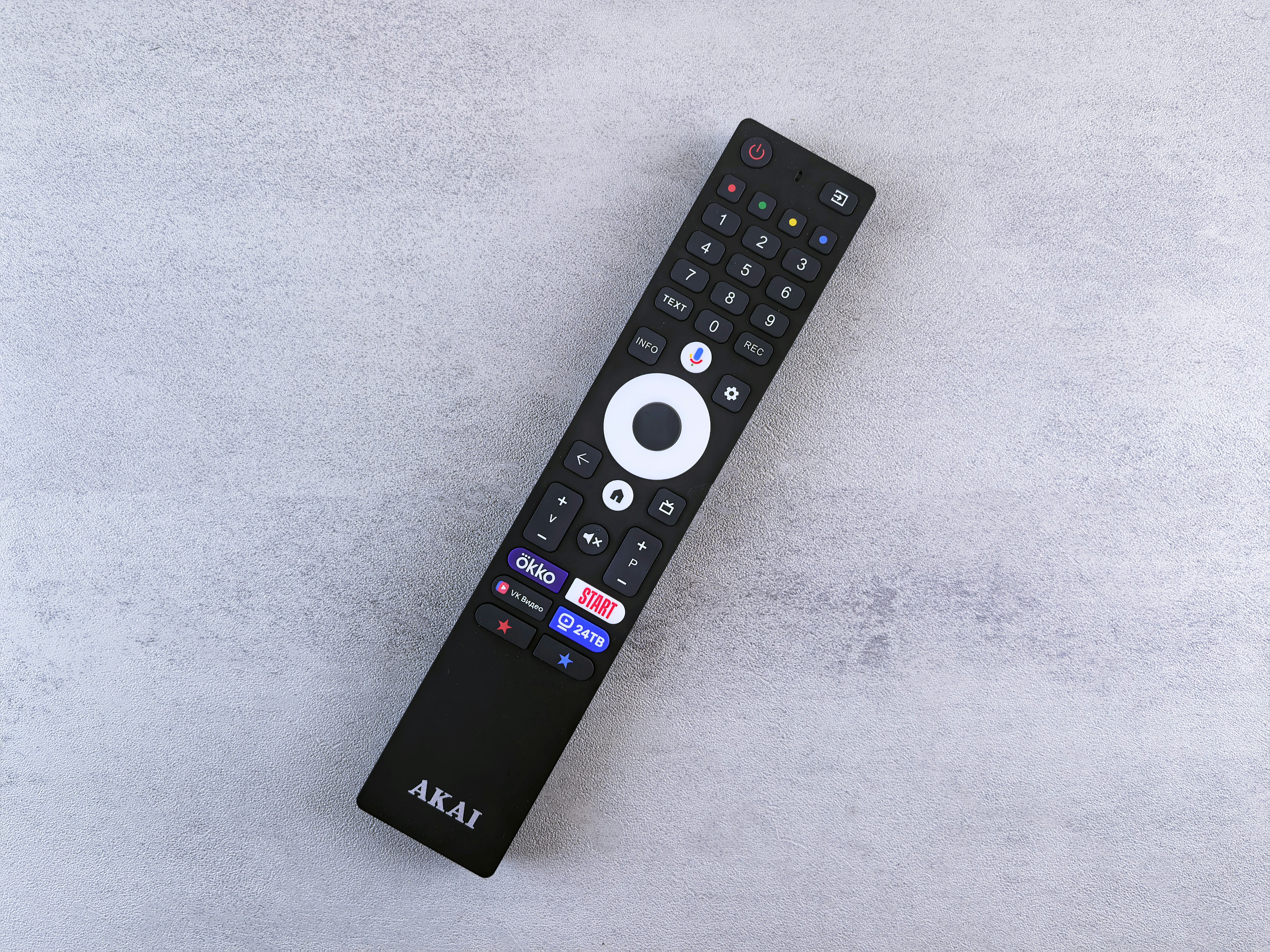 Black akai remote control on a grey surface