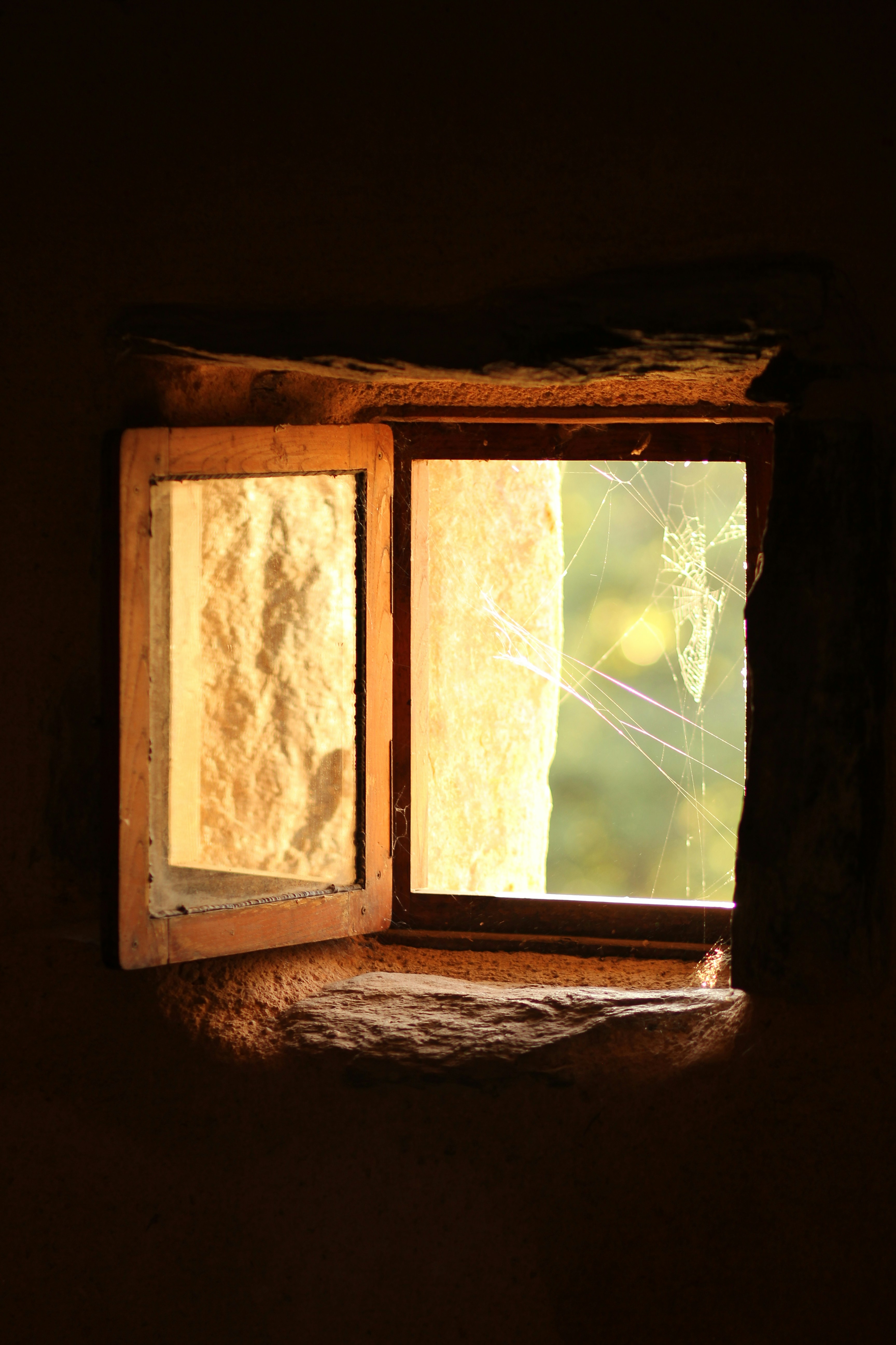 Open window with sunlight illuminating stone wall