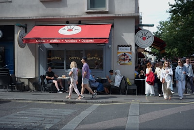 People walk past a cafe with outdoor seating.