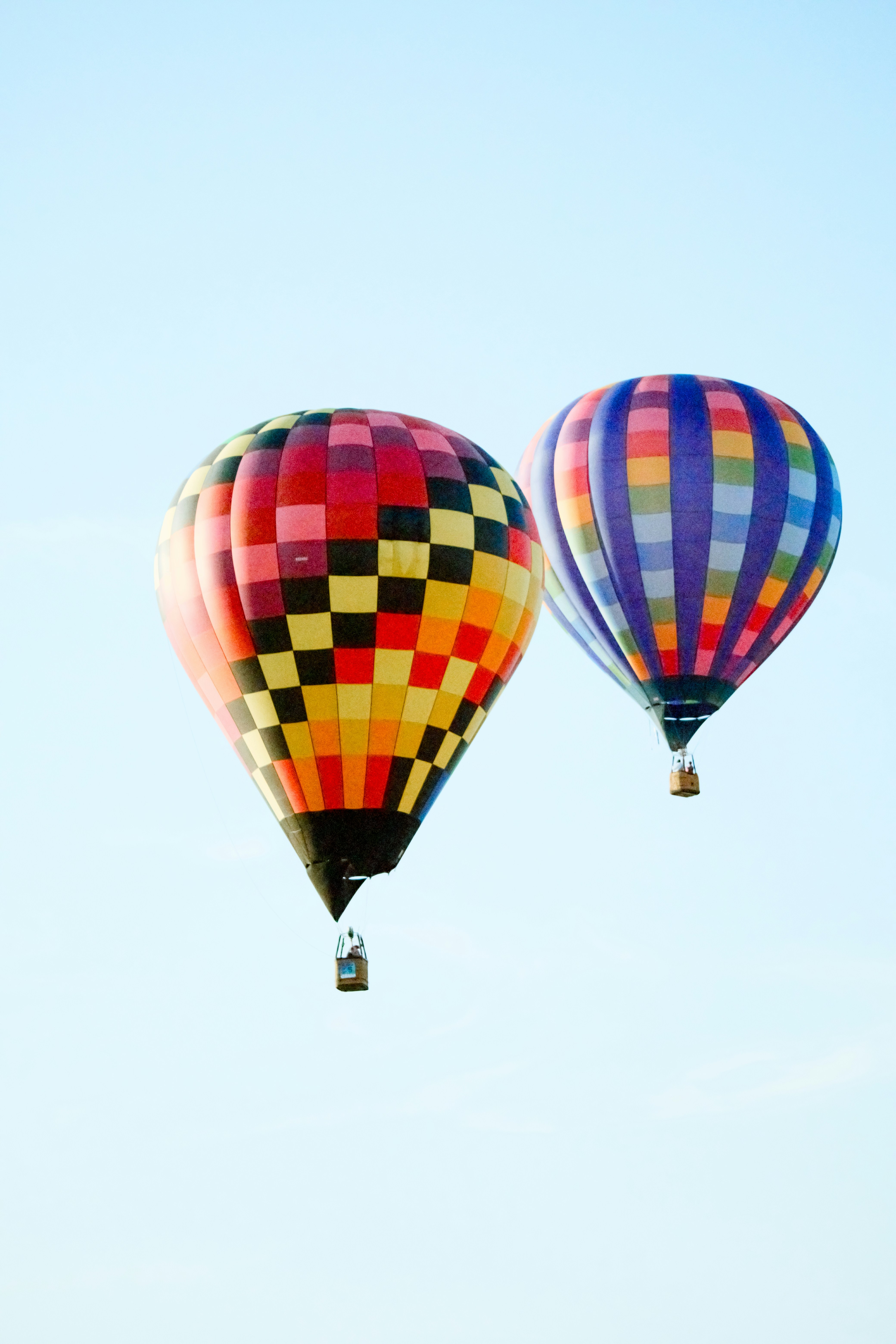 Dos globos aerostáticos de colores flotando en el cielo.