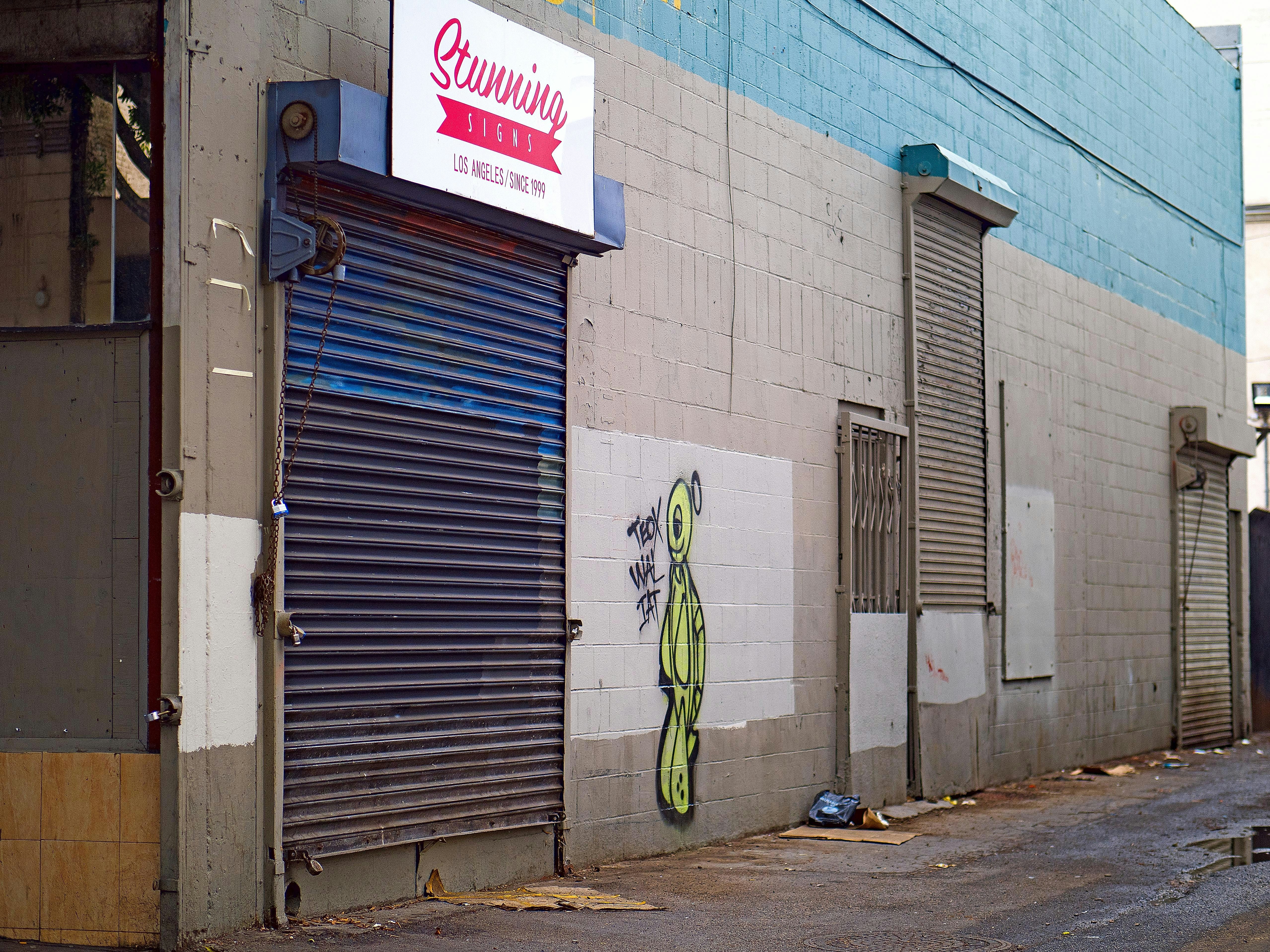 Graffiti on a weathered alley wall with closed shutters.