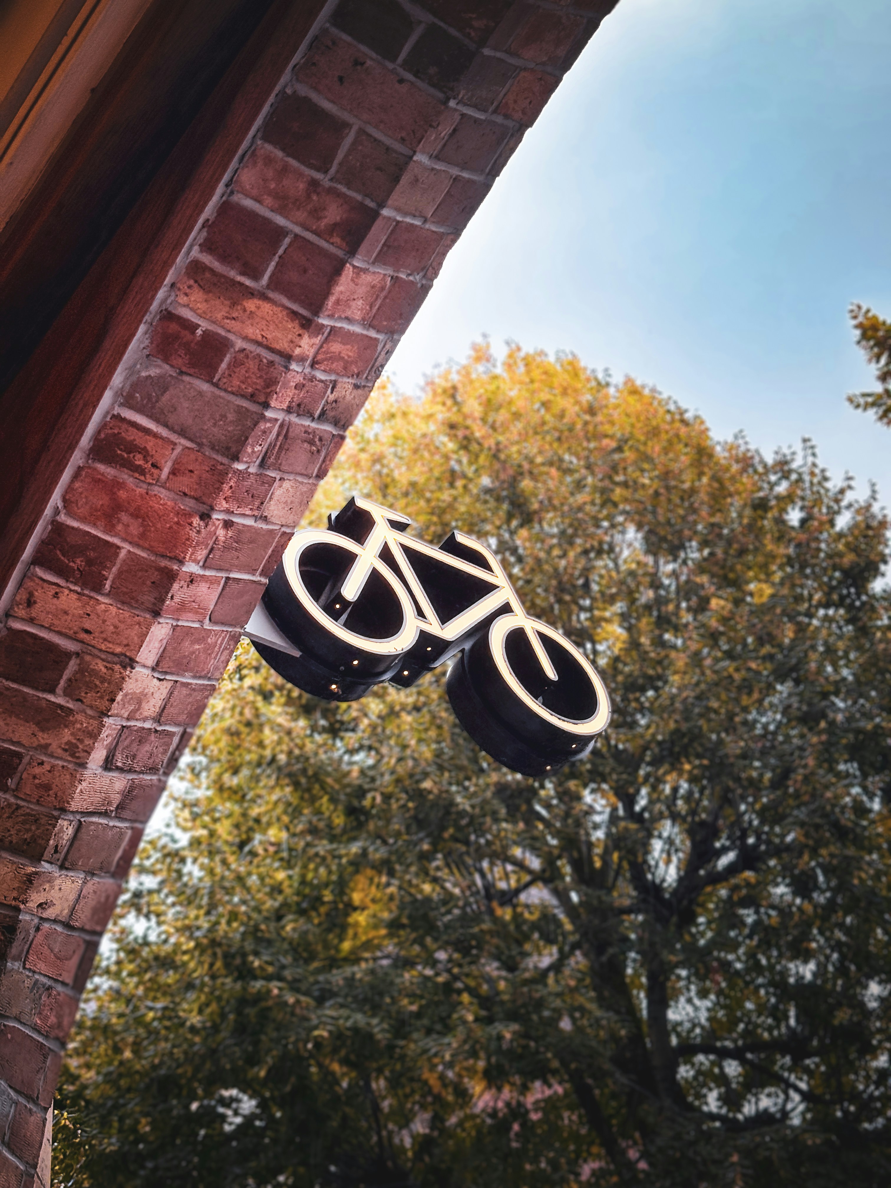A decorative bicycle sign attached to a brick archway.