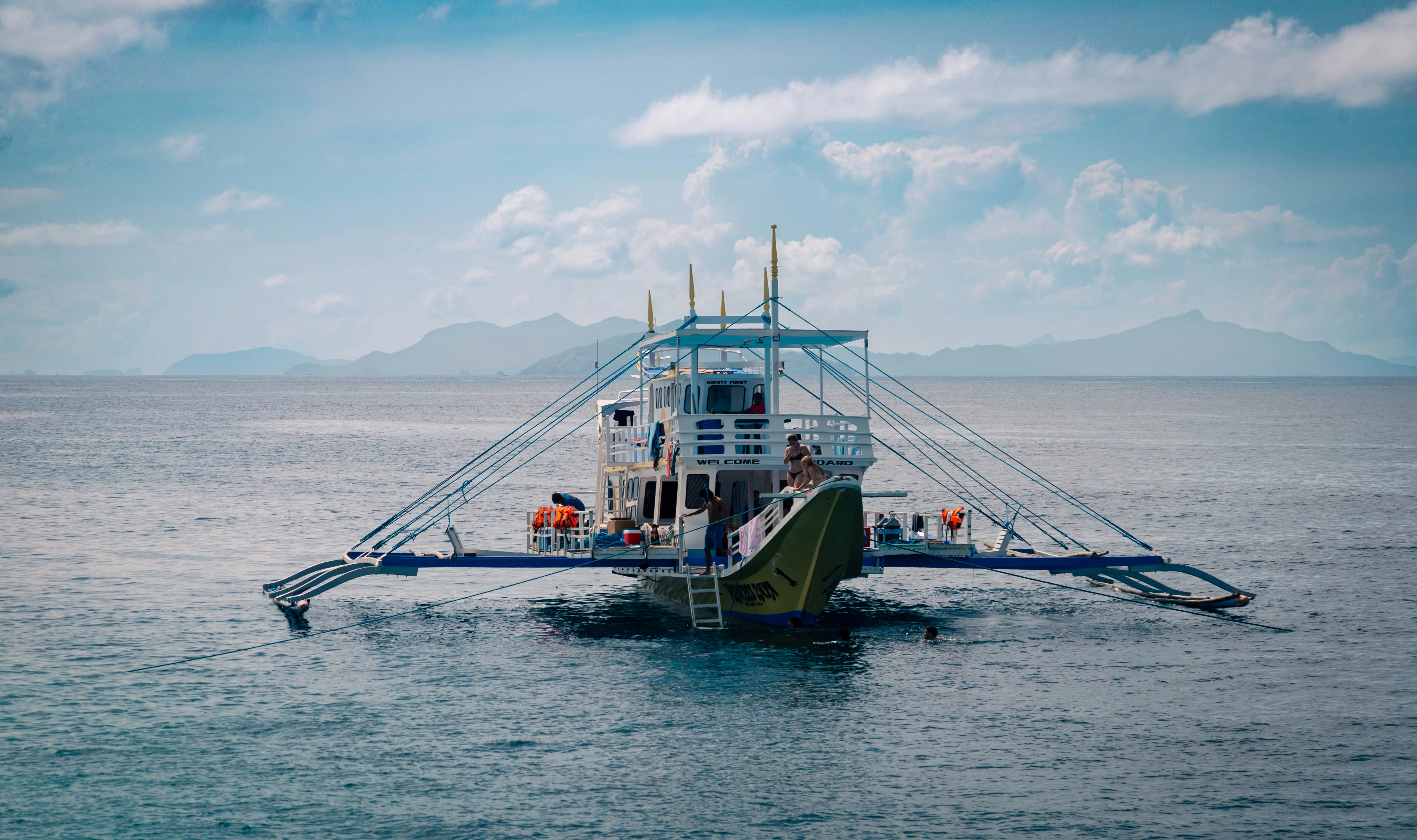 A traditional outrigger boat floats on the calm sea.