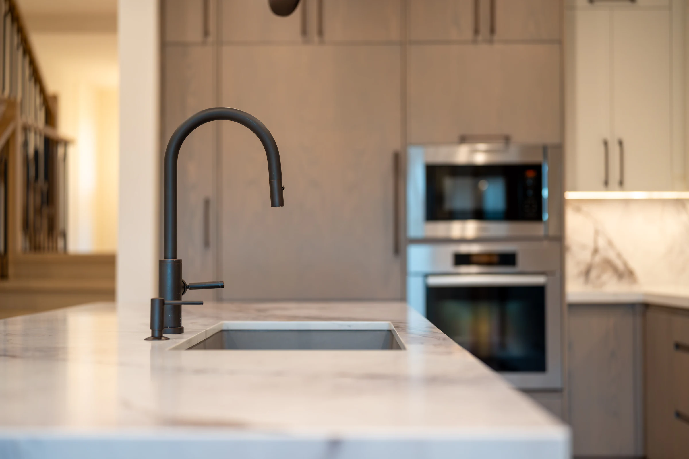 Modern kitchen island with a matte black faucet, undermount sink and marble counter