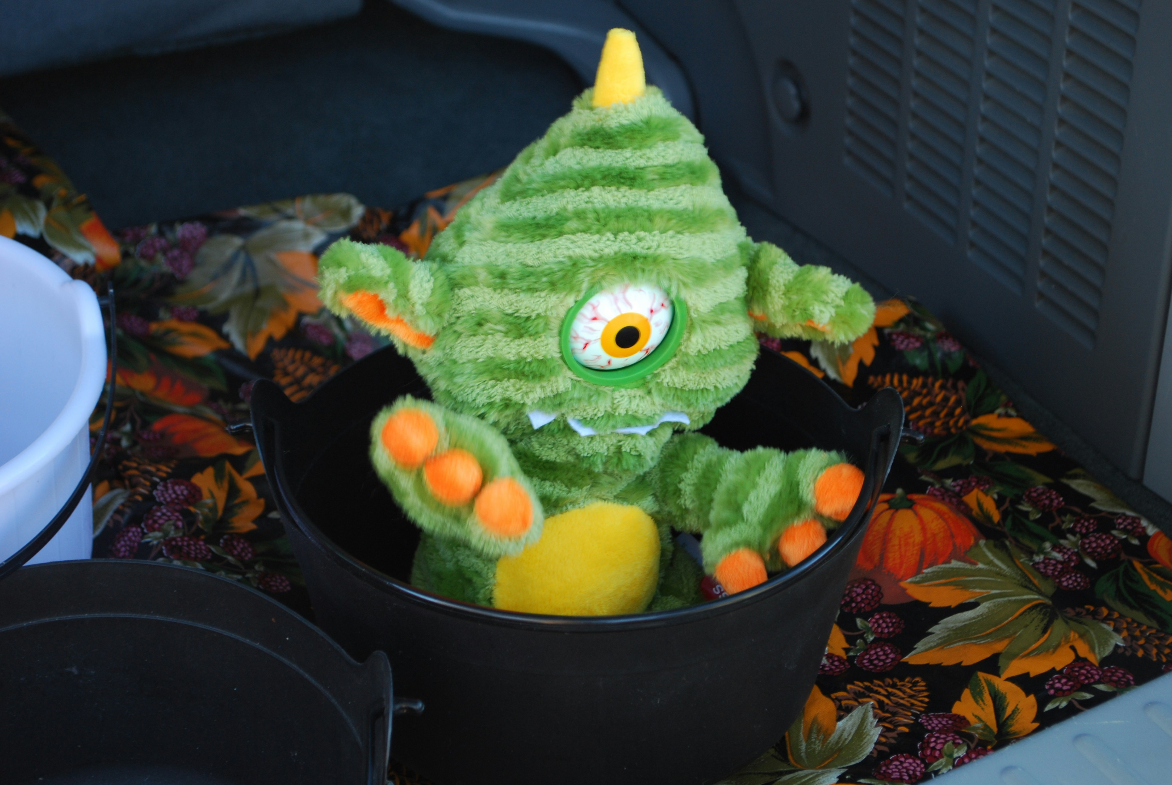 Green monster plush toy sits in a bucket