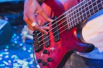 Musician playing a red electric bass guitar