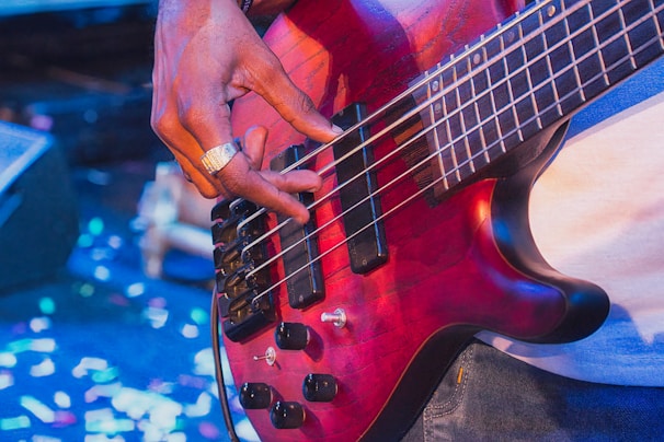 Musician playing a red electric bass guitar