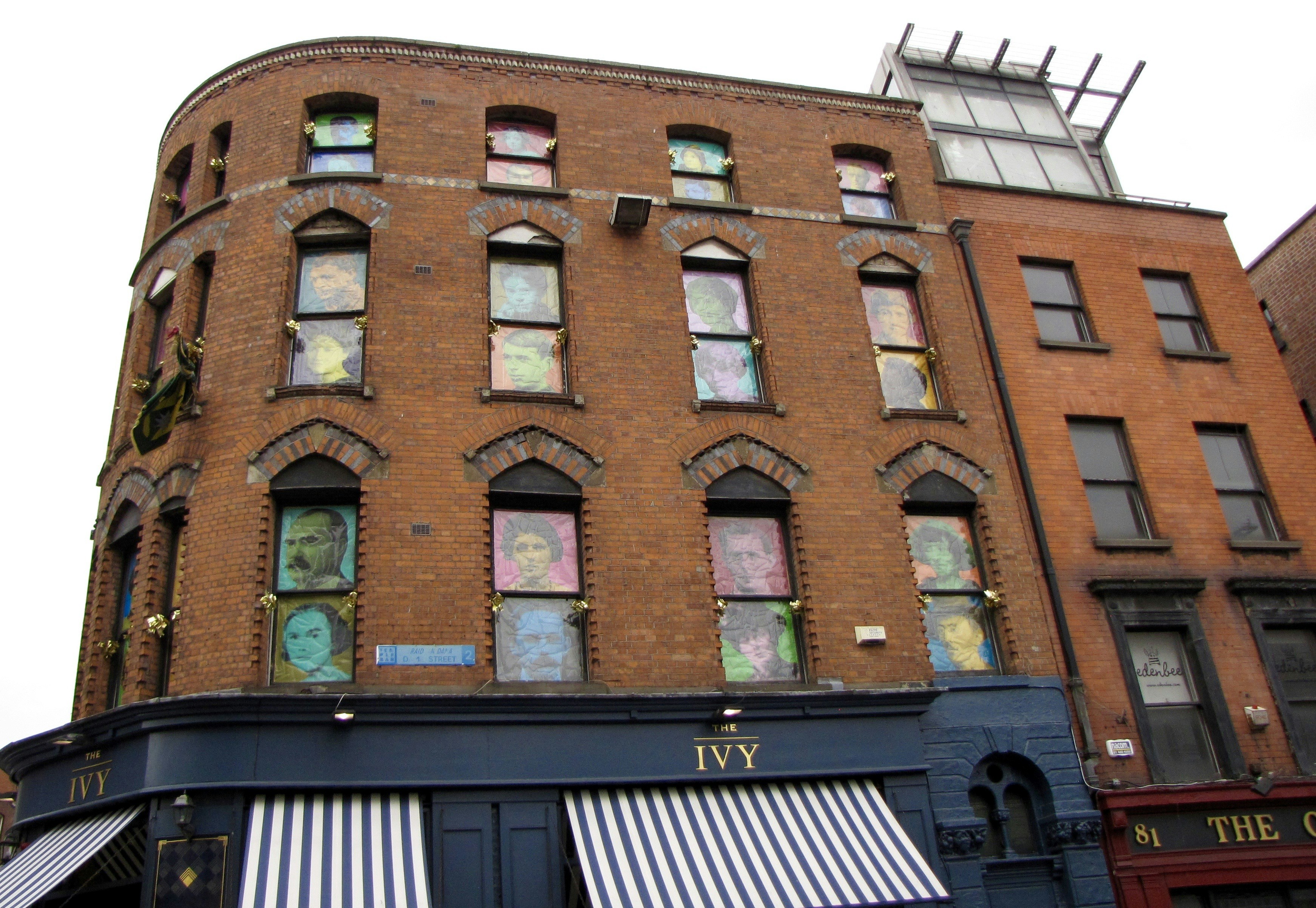 Brick building with colorful portraits in windows.