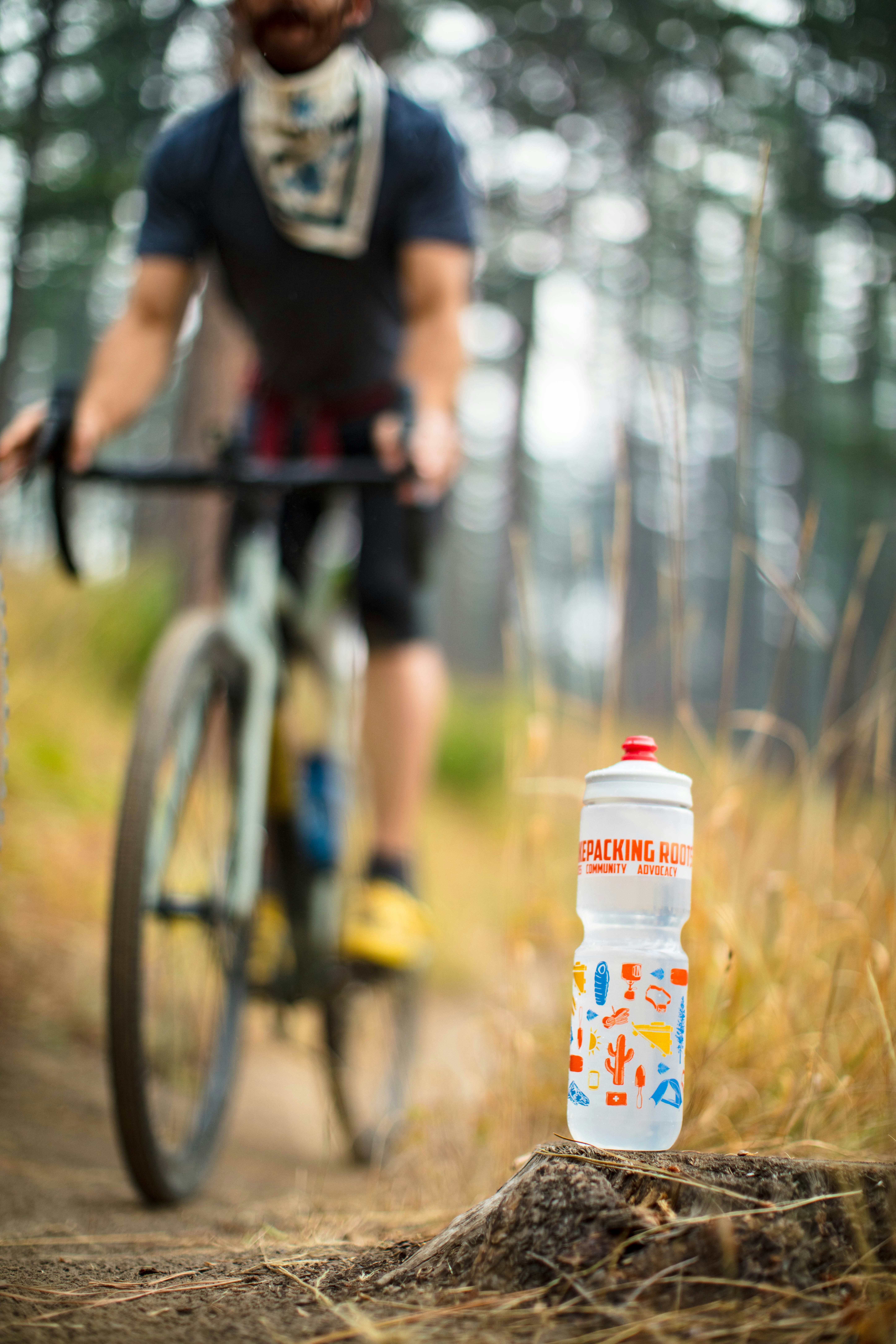 Water bottle on trail with cyclist in background