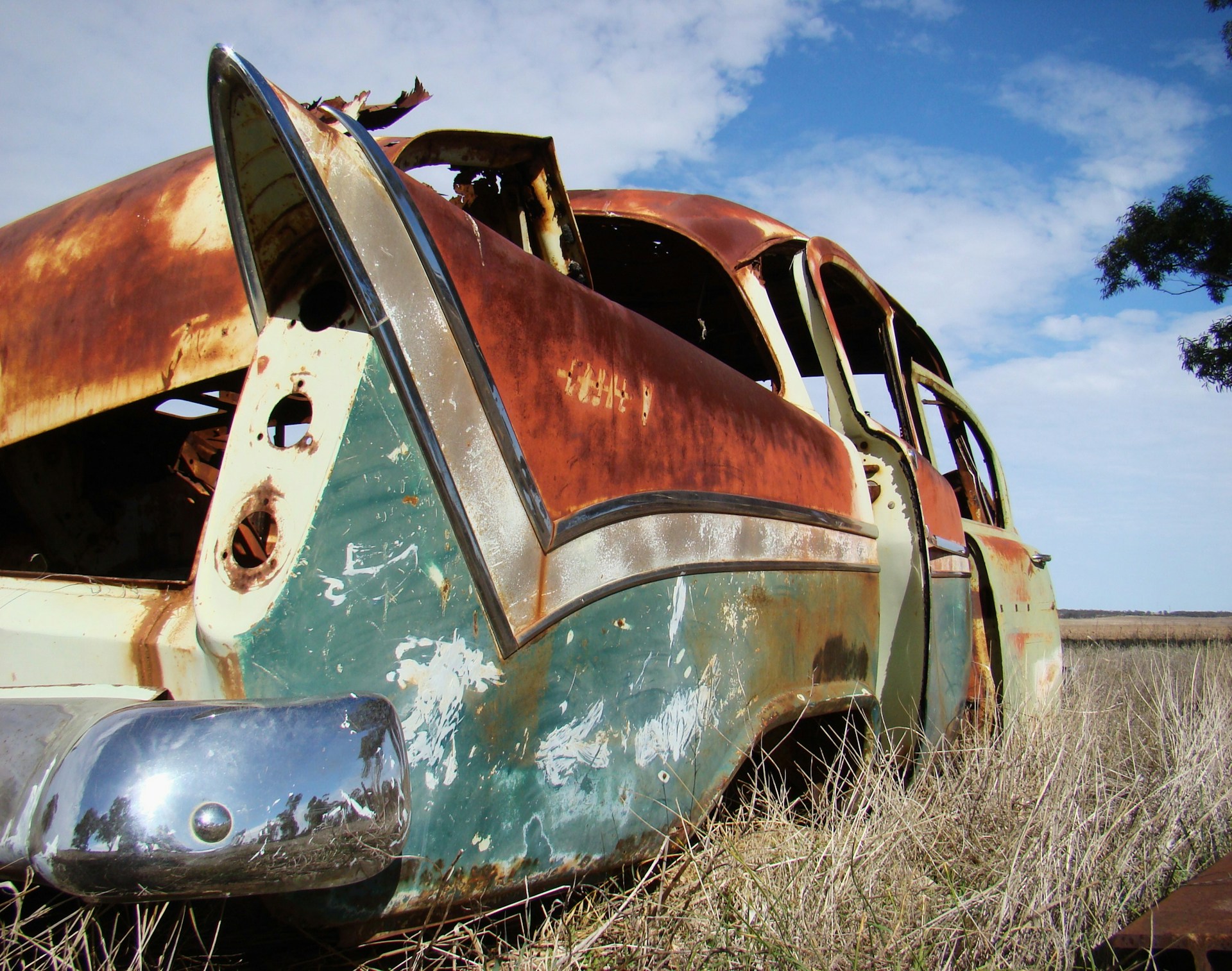 Rusted vintage car abandoned in overgrown field