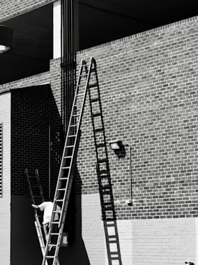 Man climbs ladder against brick wall