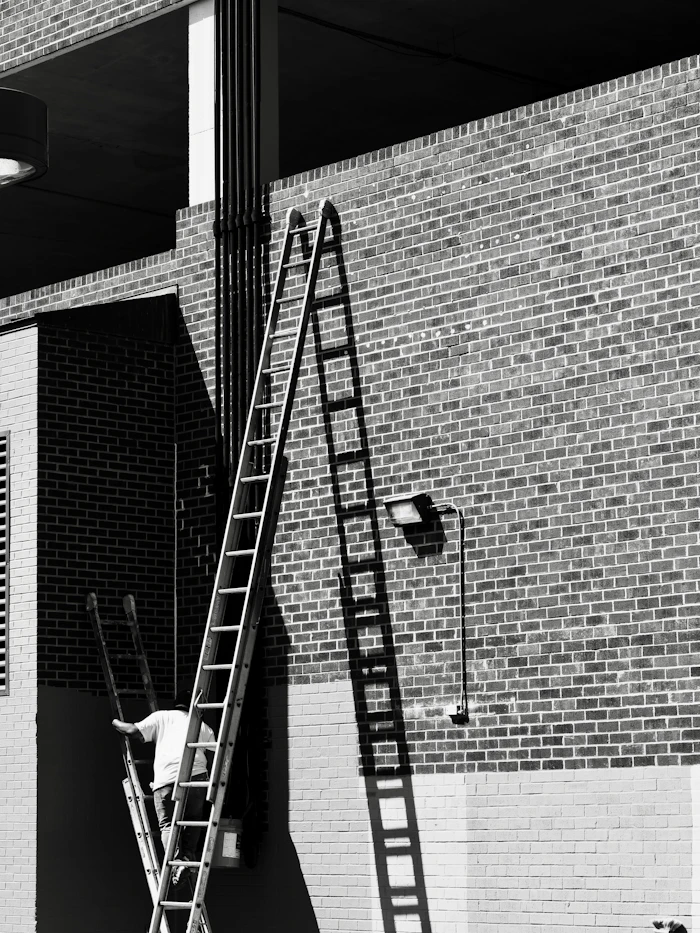 Maler steigt für Außenanstrich eine Leiter an der Fassade hoch