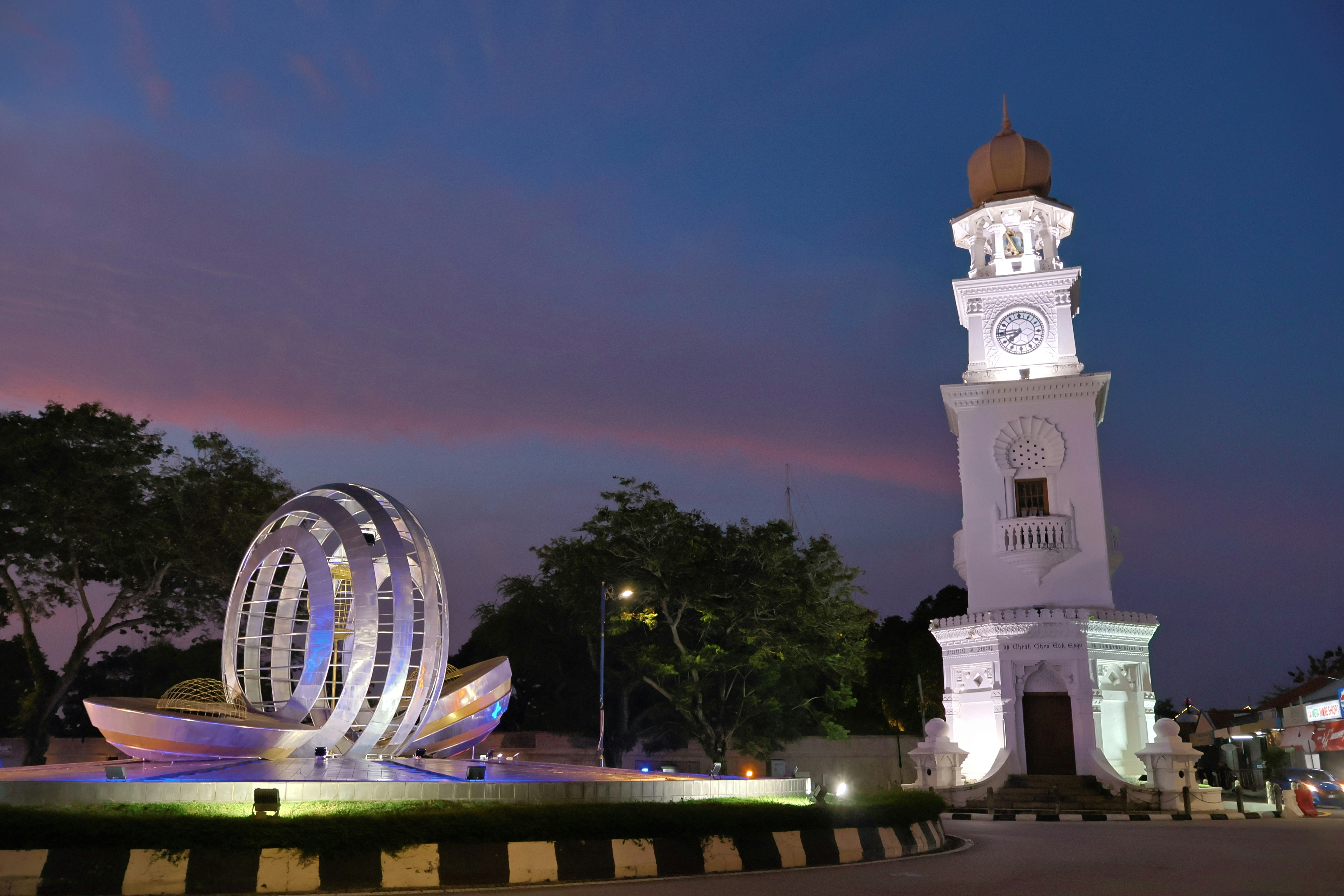 Clock tower and modern sculpture at dusk