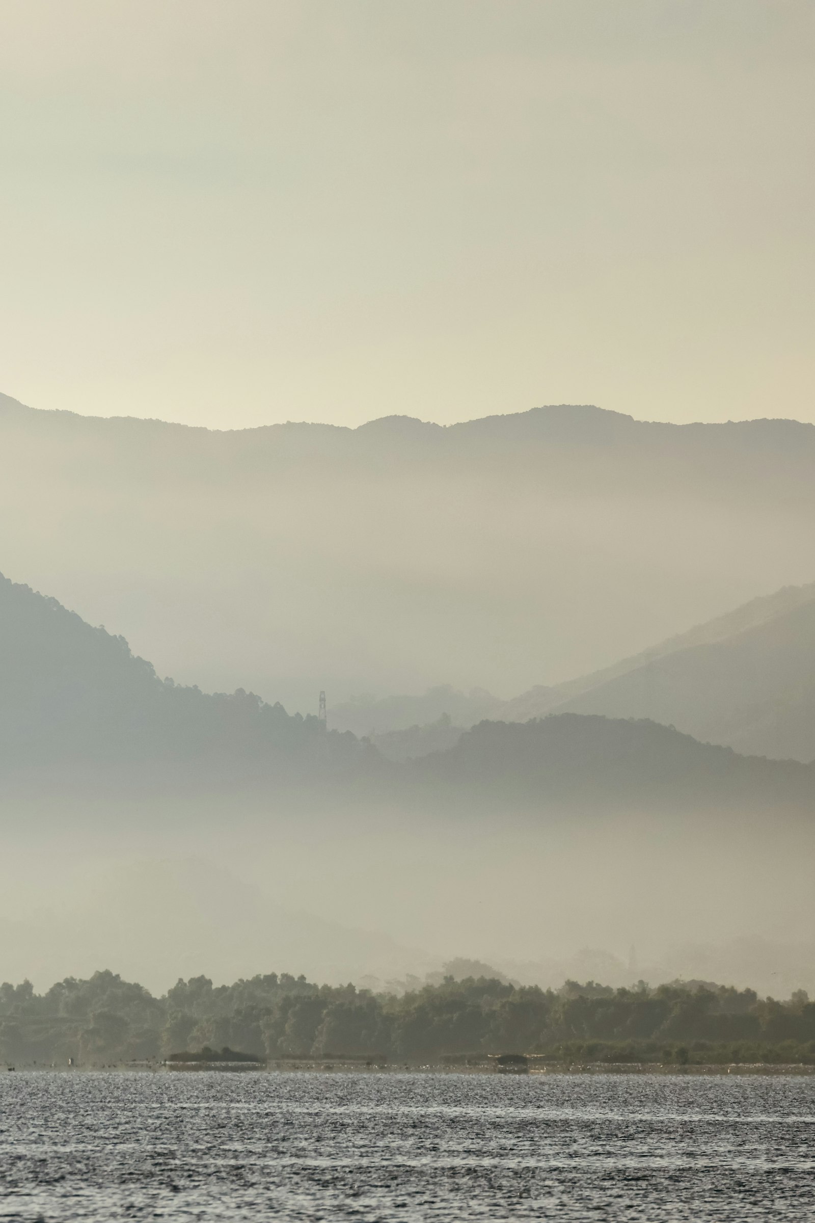 Misty mountains rising above a tranquil lake at dawn, evoking the inner stillness Eckhart Tolle and A Course in Miracles both point toward