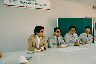 Four men sit at a table during a meeting.