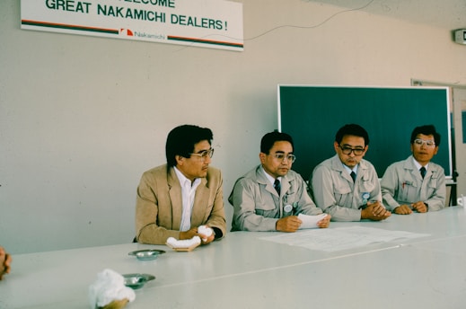 Four men sit at a table during a meeting.