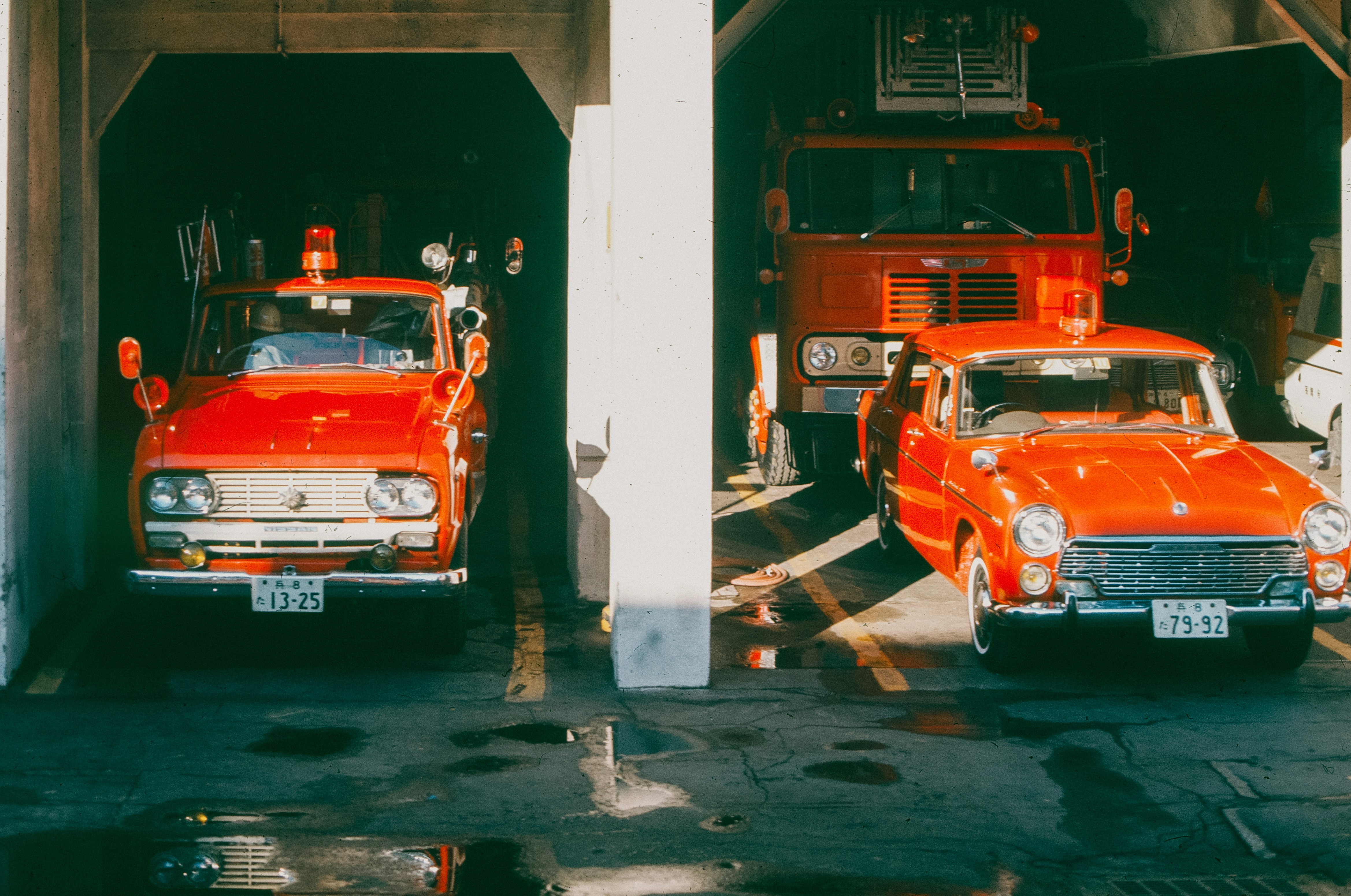 Two red fire trucks parked in a garage.