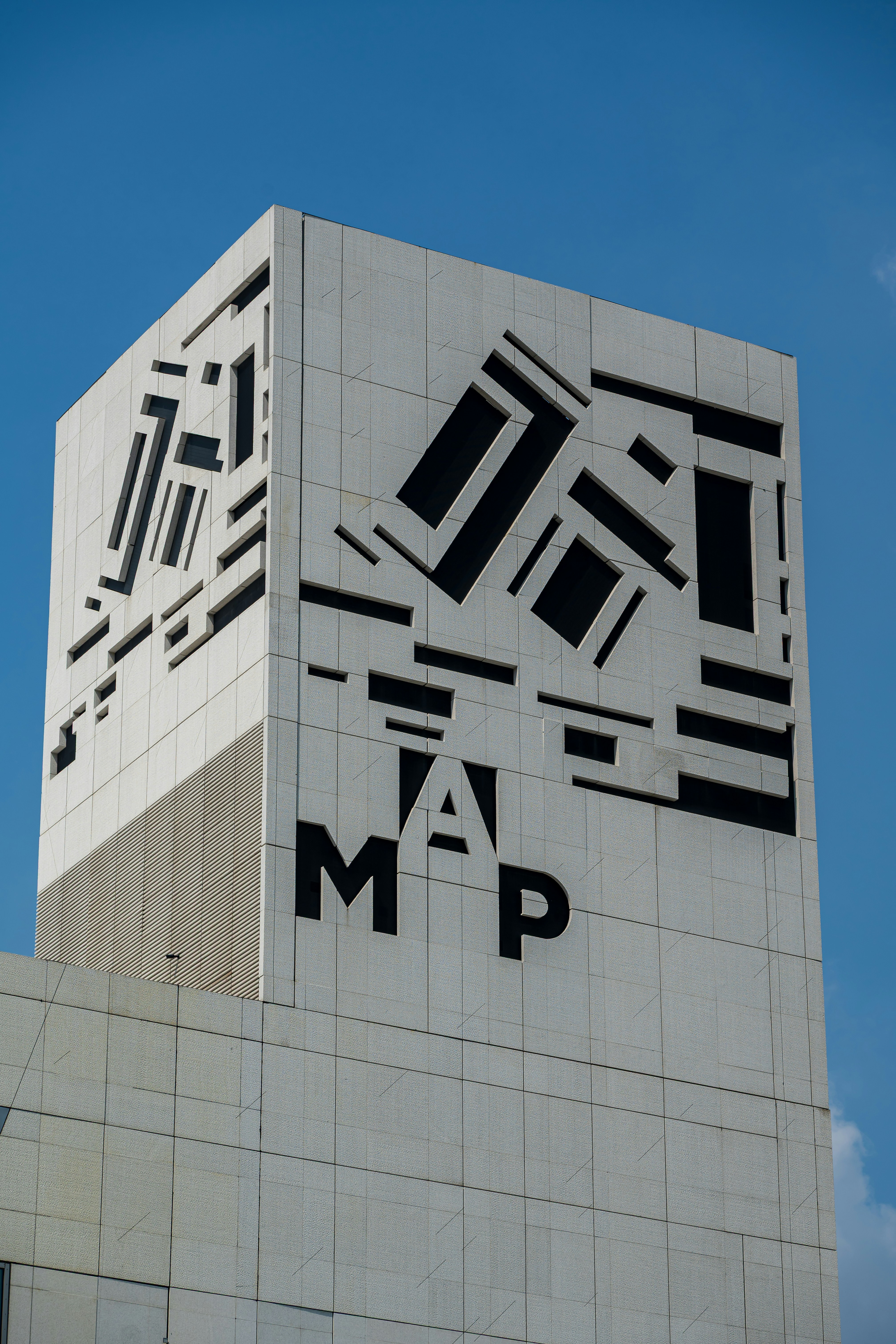 Modern building with abstract geometric facade and letters.