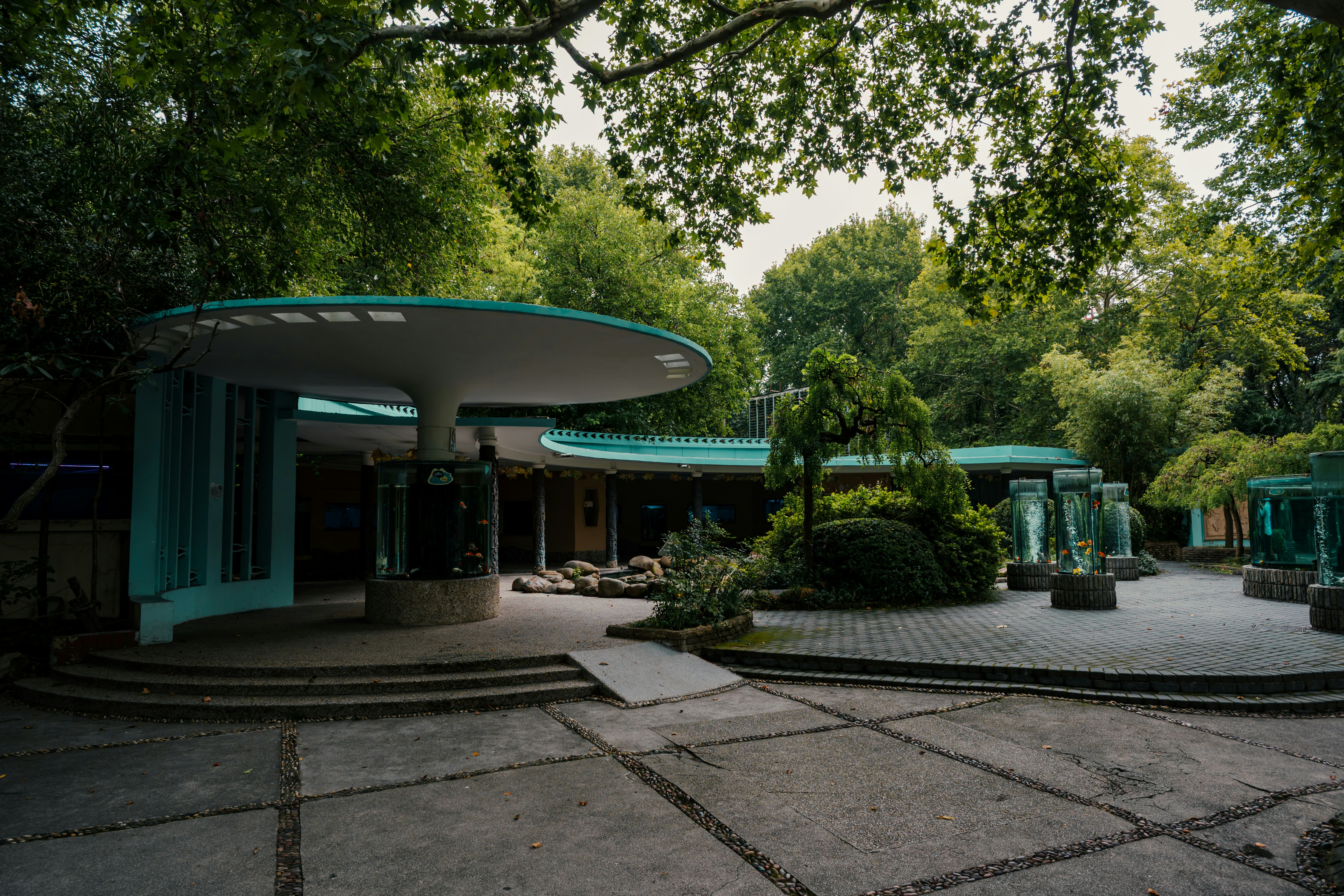 Modern building with curved roof surrounded by trees.