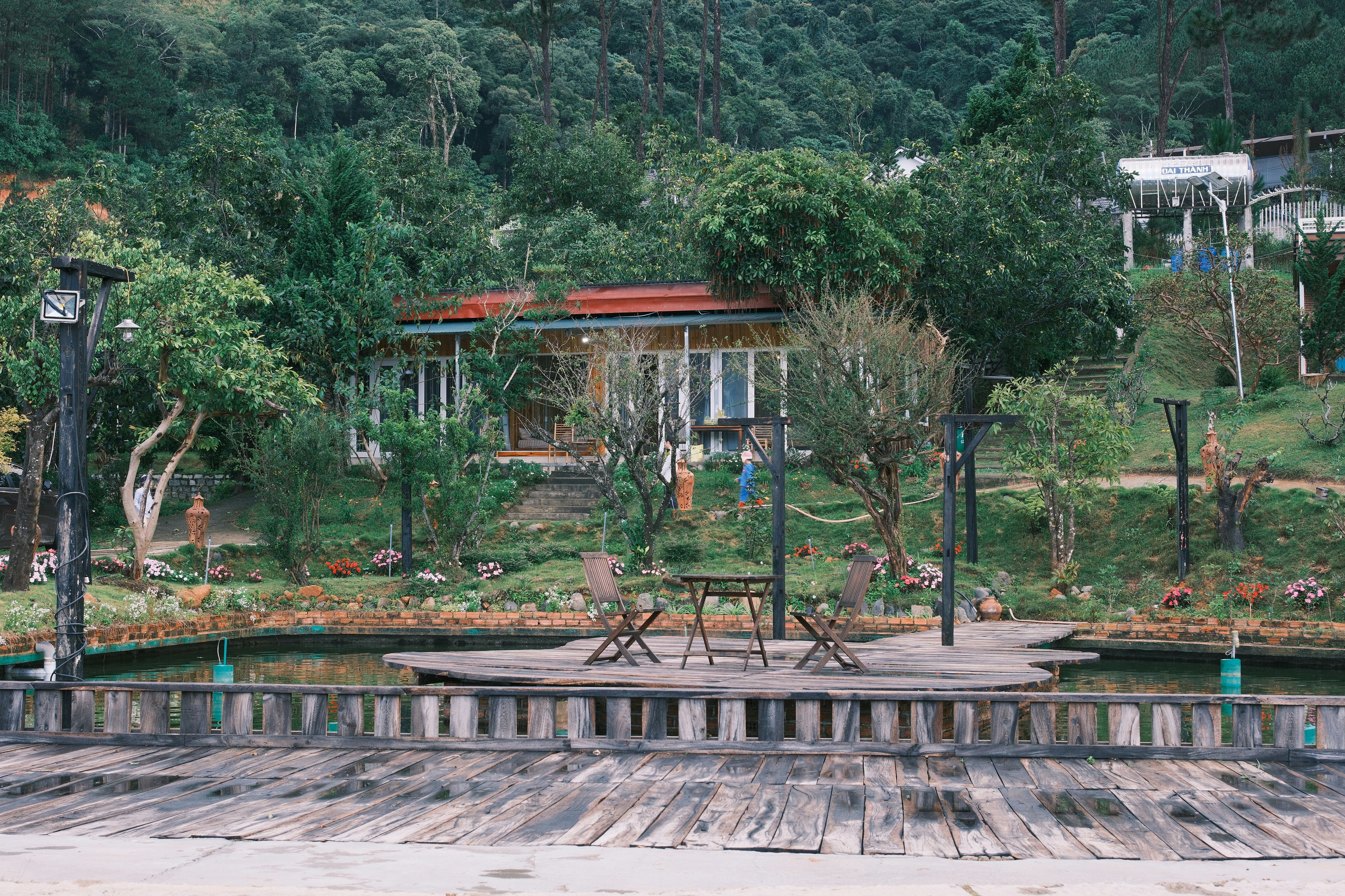 Wooden deck with chairs overlooks lush green hillside houses.