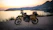 Motorcycle parked on a cliff overlooking the ocean at sunset.