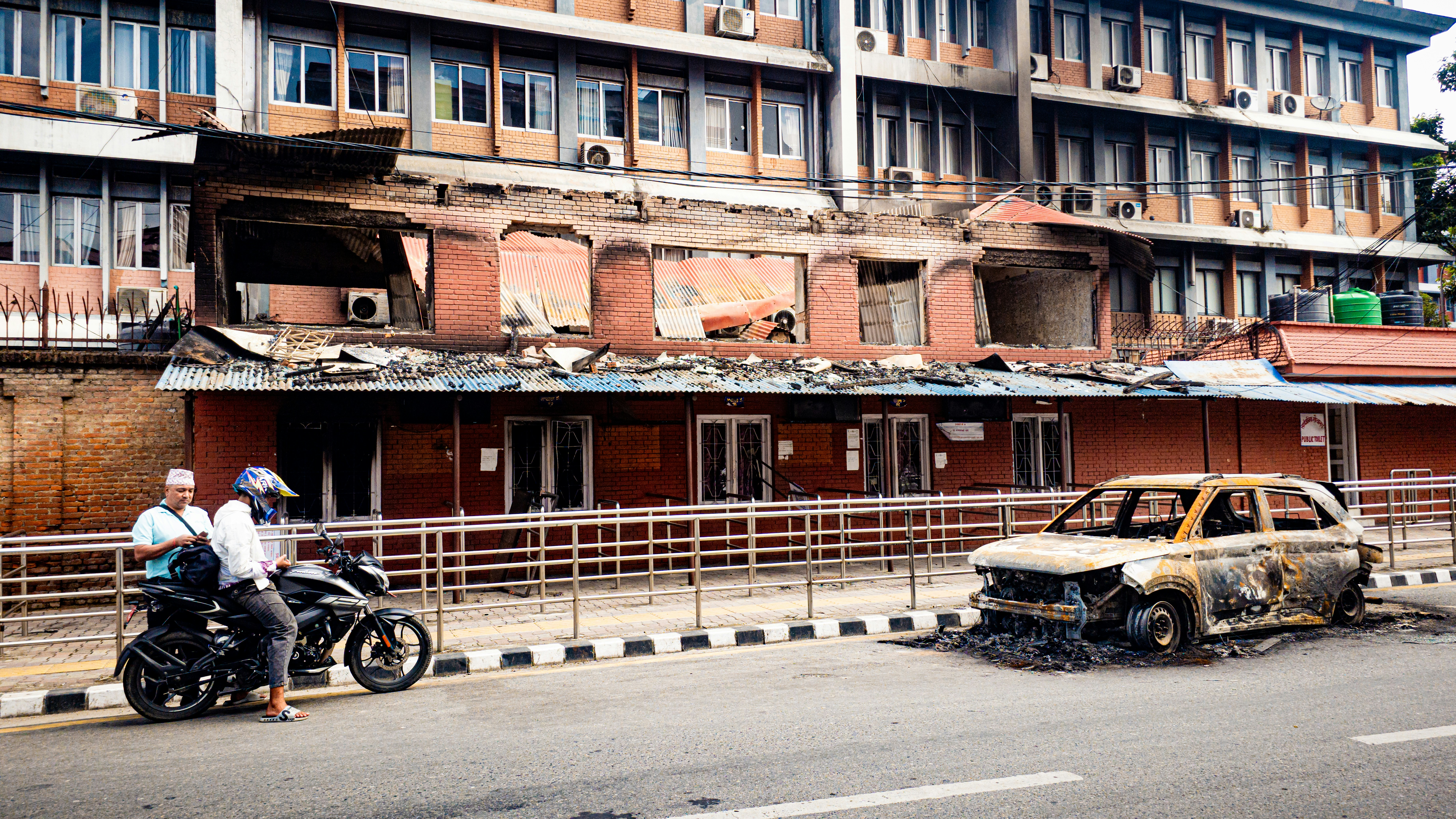 Damaged building and burnt car on street