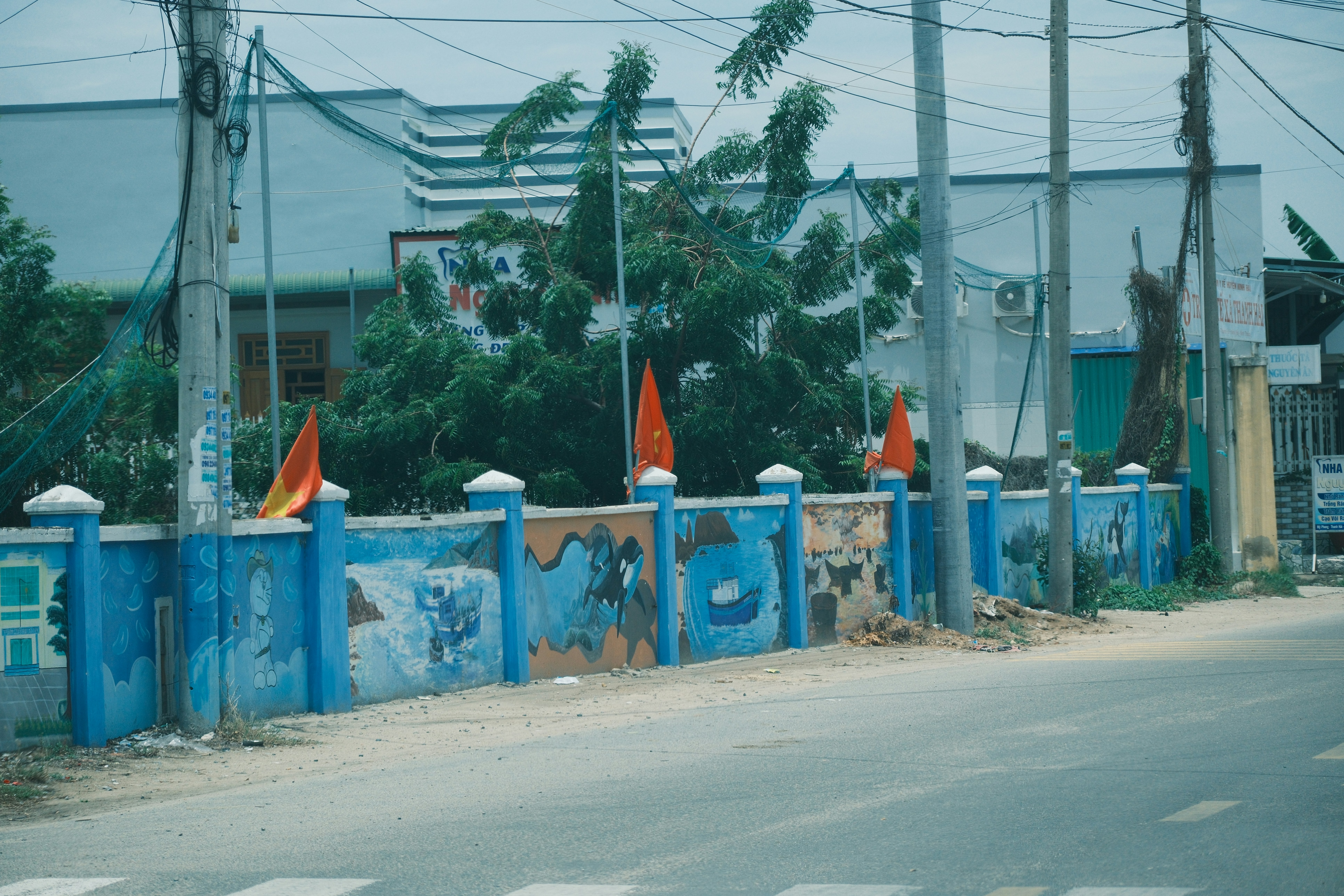 Blue wall with orange flags and graffiti near road
