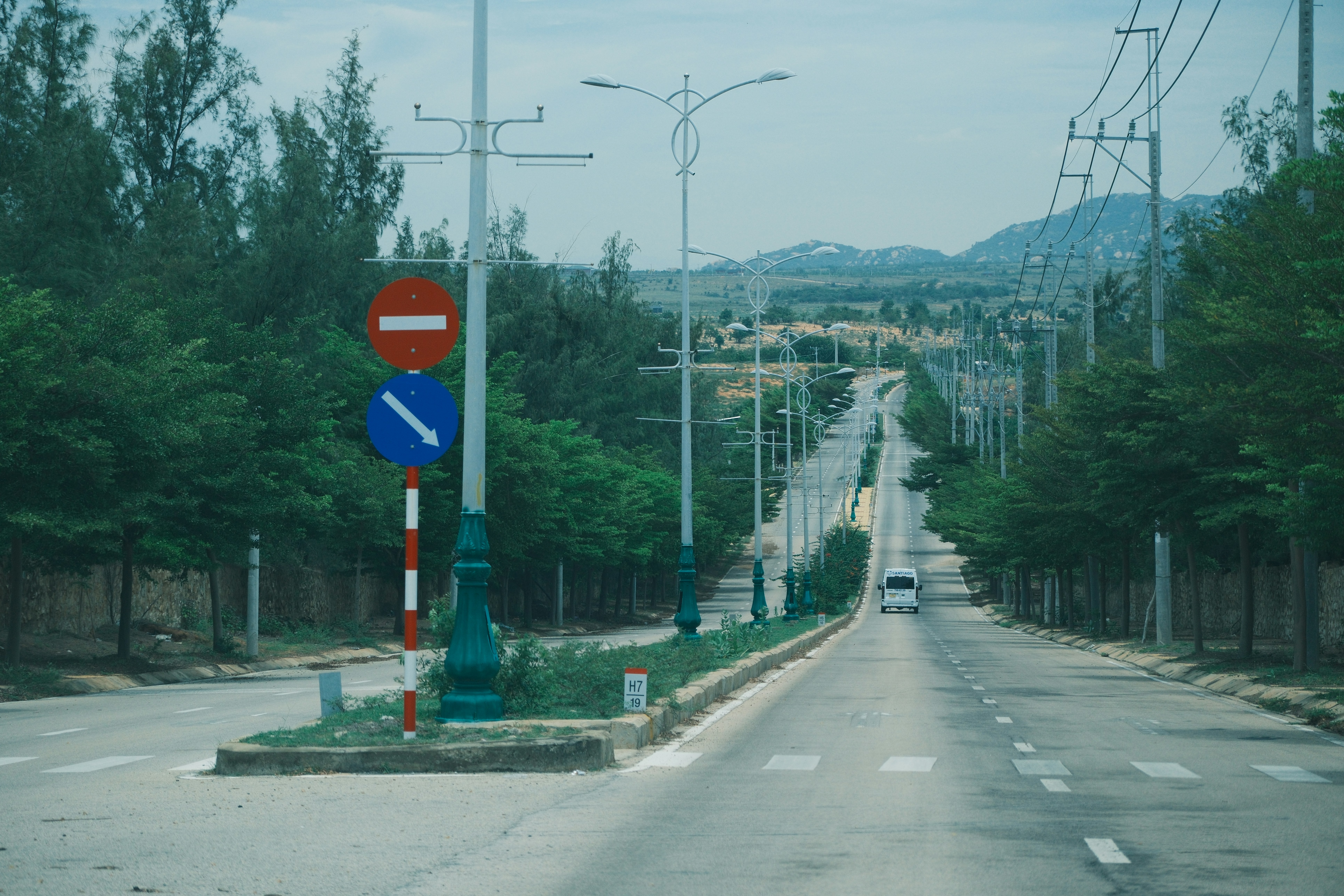 A long, empty road lined with trees and streetlights.
