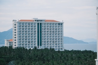 Large white hotel building overlooking the ocean.
