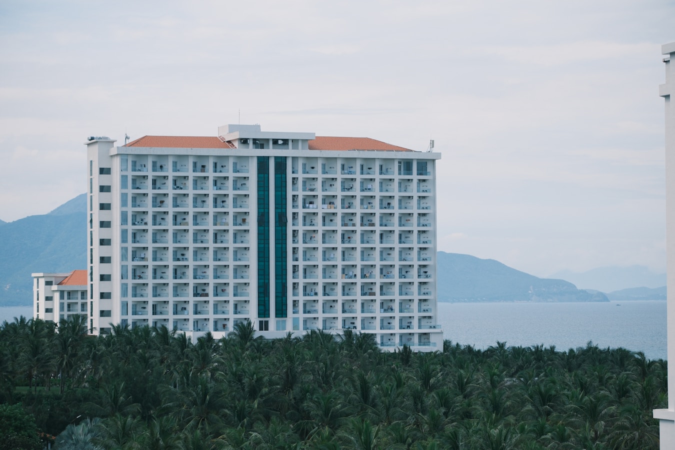 Large white hotel building overlooking the ocean.