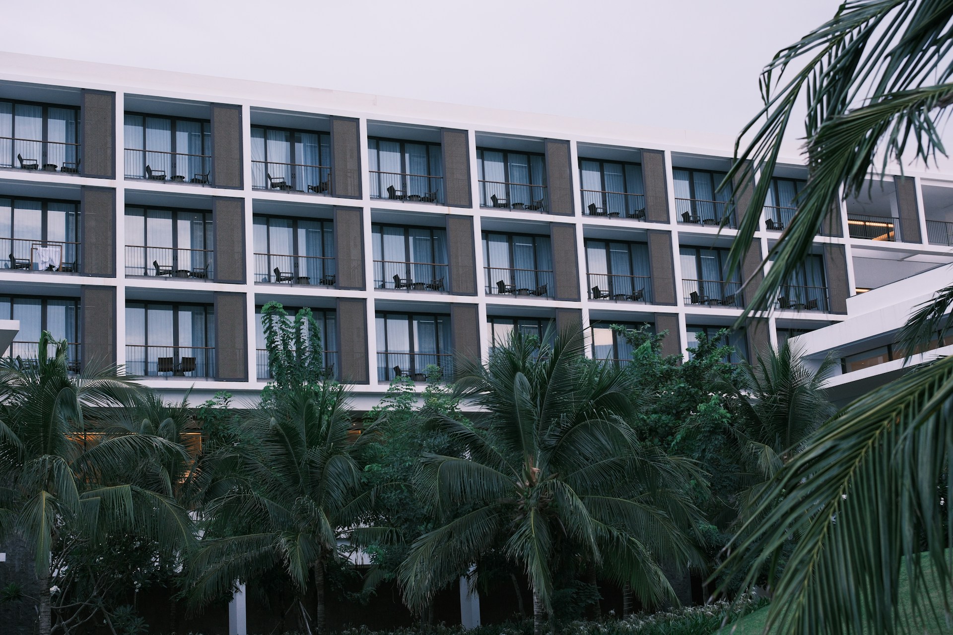 Modern hotel building with balconies and palm trees