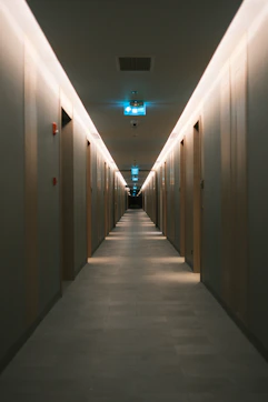 Long hotel corridor with illuminated doors and exit signs