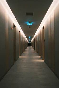 Long hotel corridor with illuminated doors and exit signs