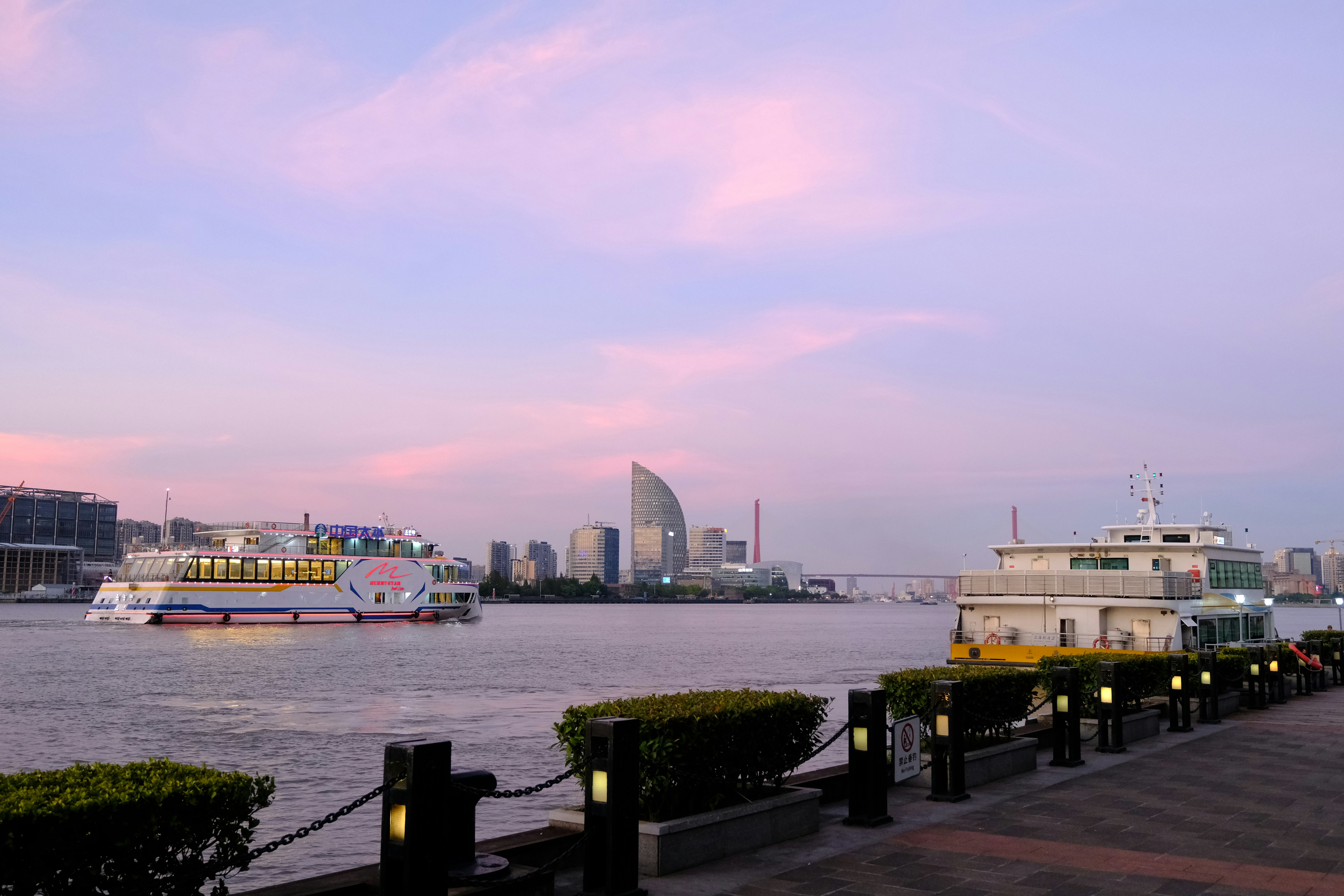 Boats on the water with a city skyline at dusk.