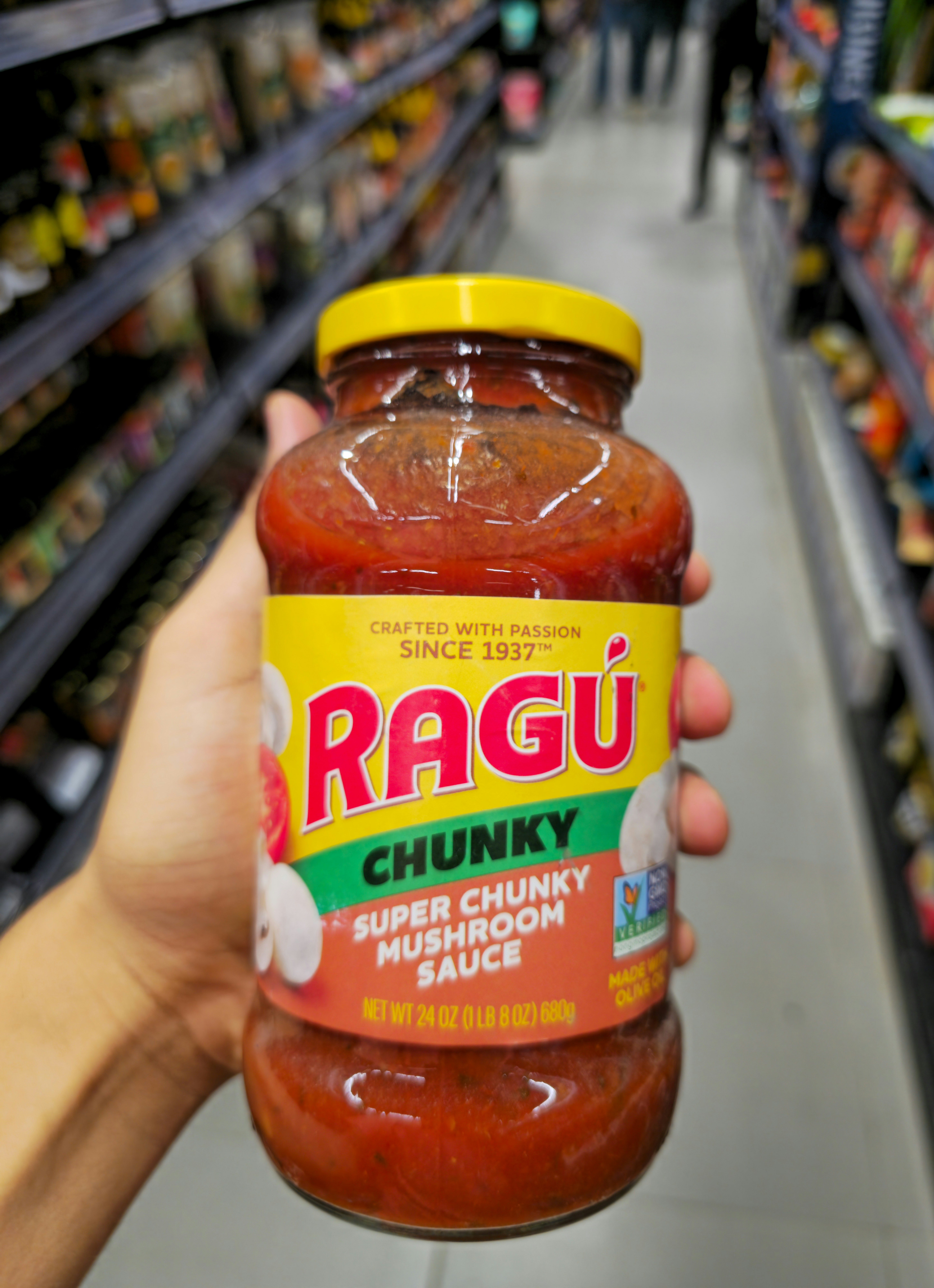 Hand holds jar of ragu chunky super chunky mushroom sauce.