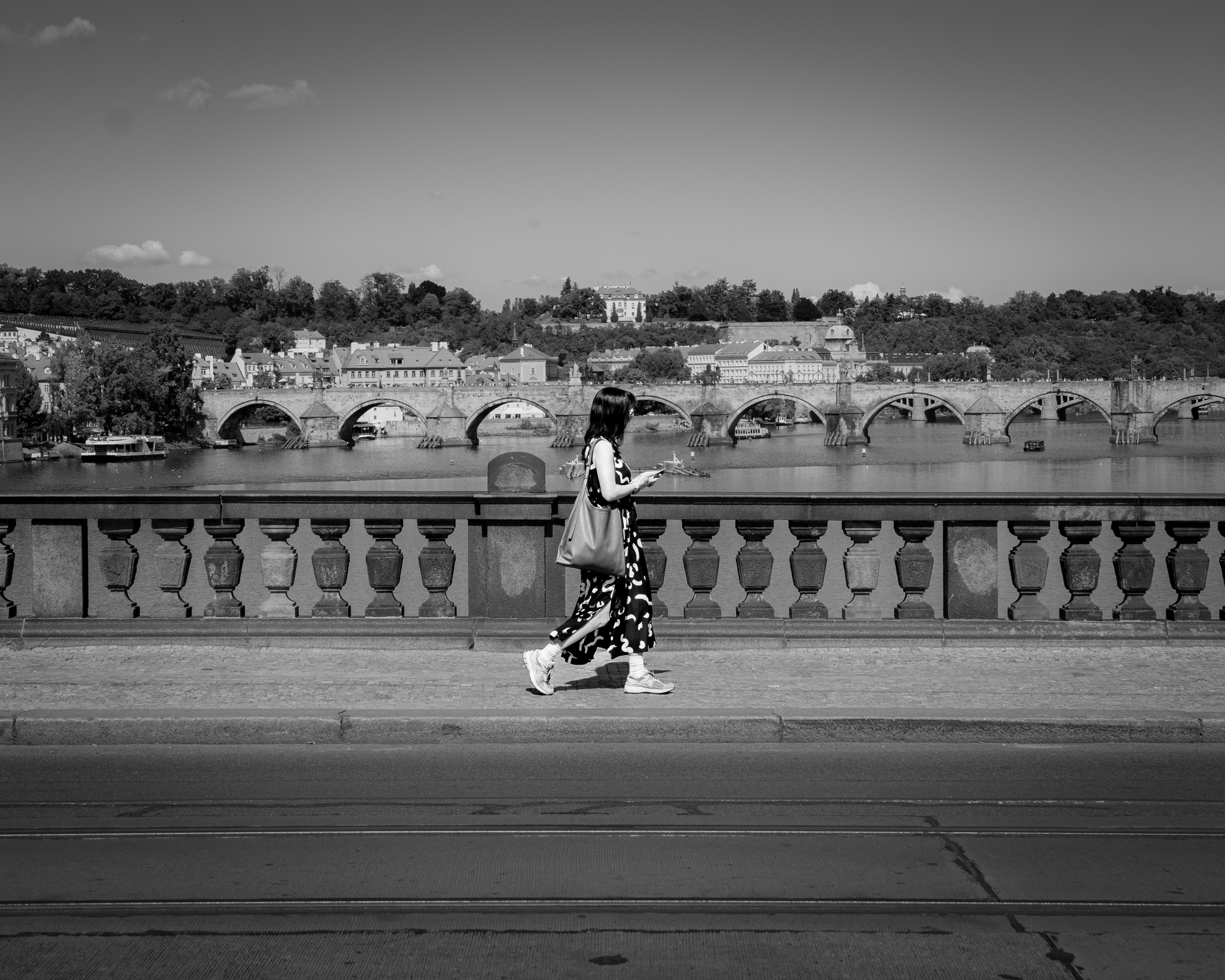 Woman walking across a bridge with cityscape background